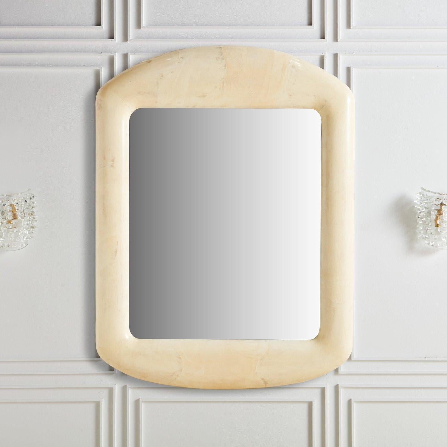 A stunning monumental rectangular wall mirror featuring a thick dome frame constructed with wood clad in goatskin and protected under a lacquer finish. The goatskin is a beautiful cream hue with subtle color variations. The scale of this mirror is