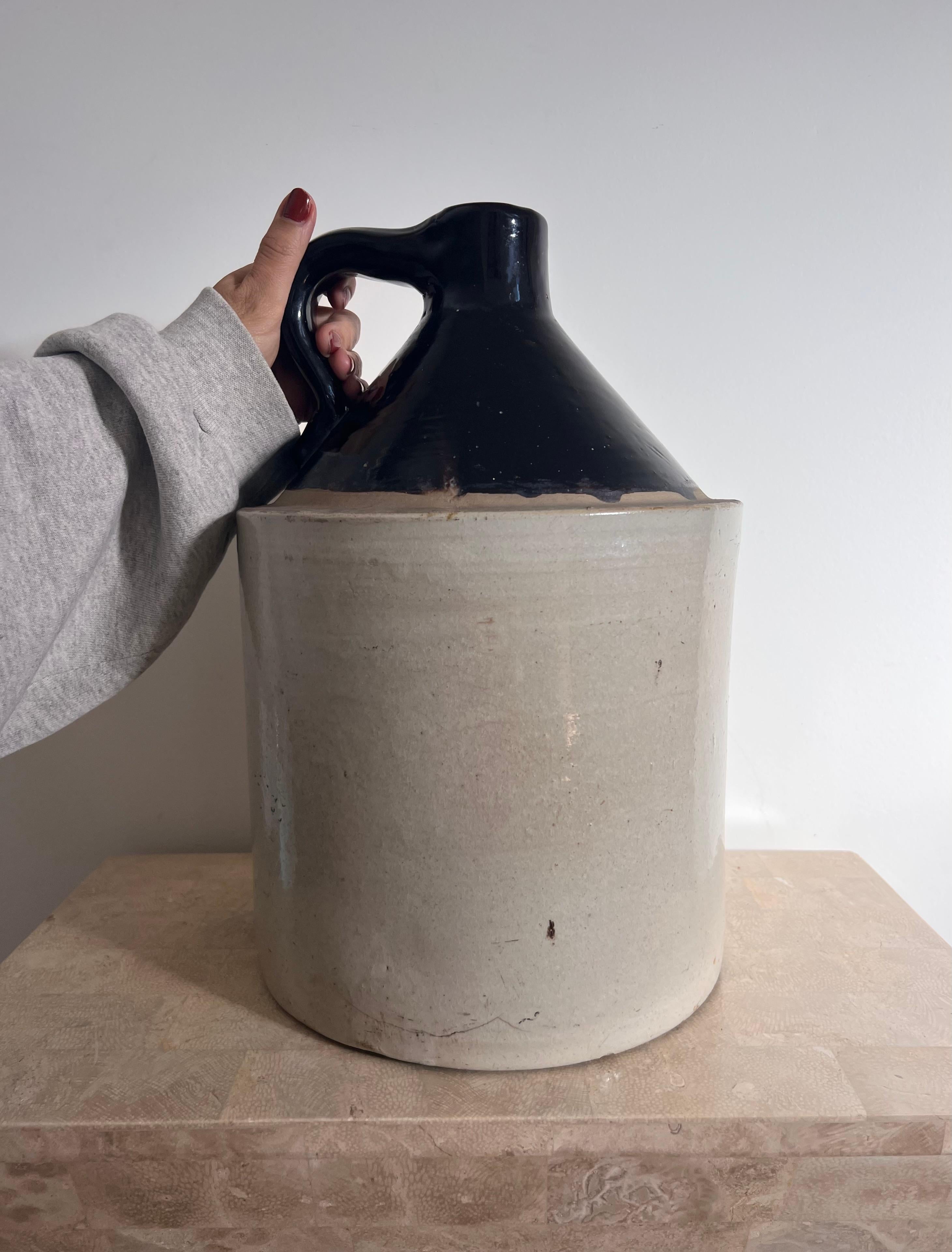 A monumental 3-gallon ceramic jug, circa 1950s. Can also be used as a pitcher or vase. The base is a muted taupe hue, while the top is glazed ceramic in a licorice tone. A “three” imprinted on a side of the jug indicates the gallonage. Very heavy.