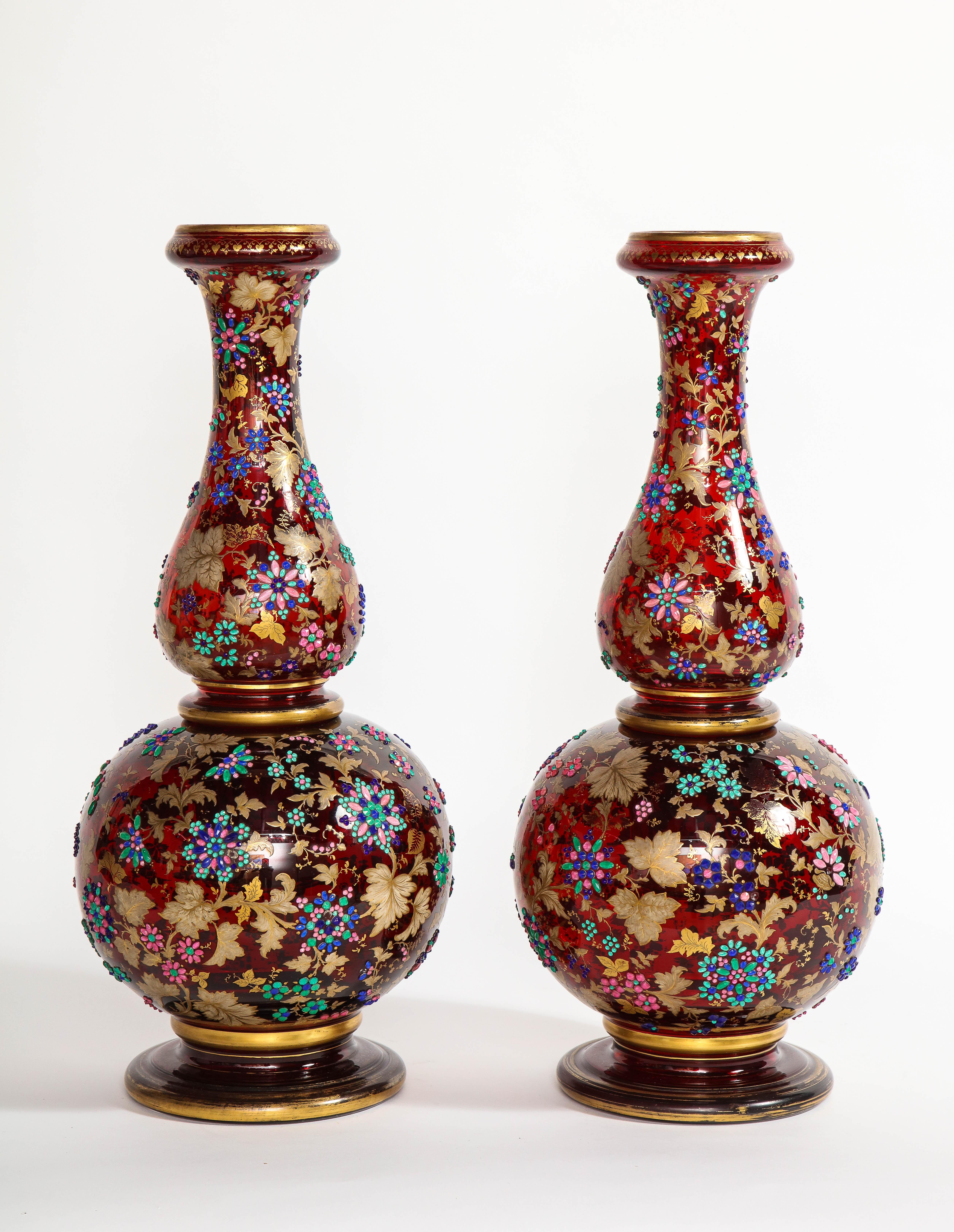 A monumental pair of antique 19th century Moser ruby-red overlay two-piece jeweled and 24-karat two toned, burnished and matte gold vases. Each of these vases are fabulously handcrafted with exquisite detail. Finely applied jewels and colored