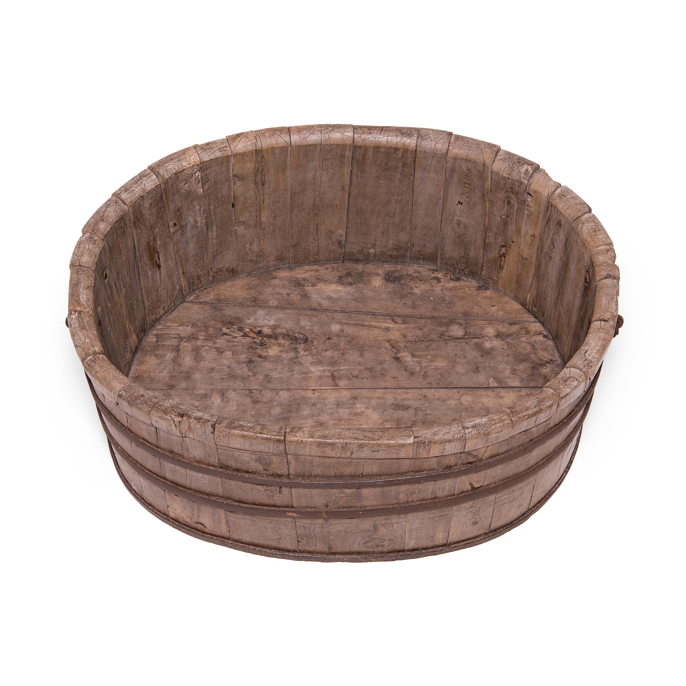 With its grand scale and perfect proportions, this rustic wooden bathtub is true showstopper. The tub has an elongated, oval shape is comprised of thick cypress wood staves held together by three iron bands. Two iron handles on either side of the
