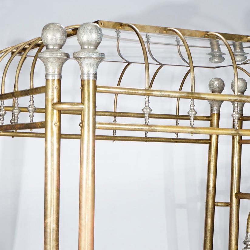 A monumental regal canopy bed offers brass construction with coved and mirrored canopy over highly decorated frame having palmette finials, turned incised gilt silver spindles with caps , 20th century

Measures- Overall 91.5'' H x 88.5'' W x 87'' D;
