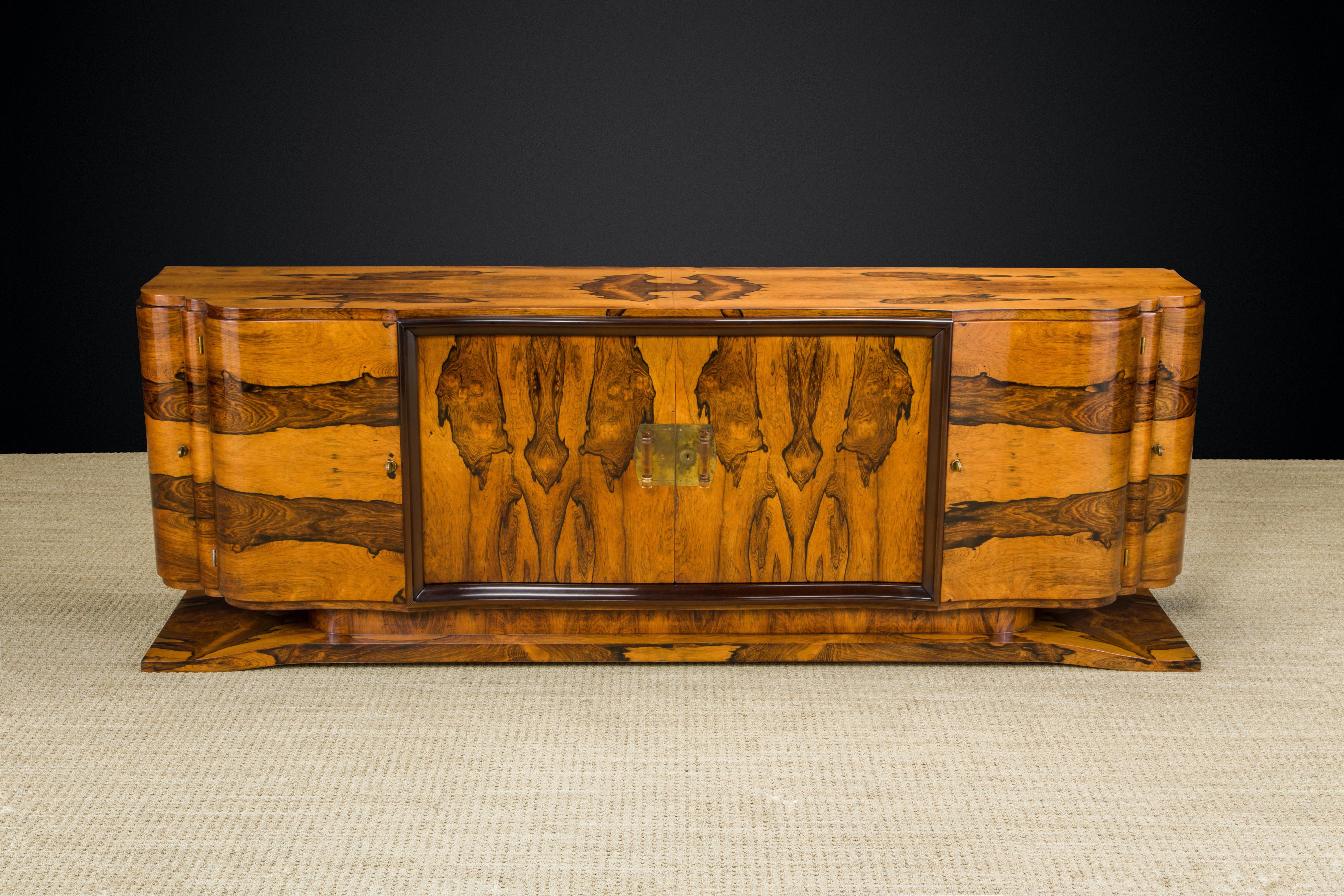 This stunning and exquisite sideboard cabinet was expertly crafted from Rosewood with brass and rose lucite center cabinet pulls. This monumentally sized cabinet was clearly an important piece as its craftsmanship and materials are first-class. The