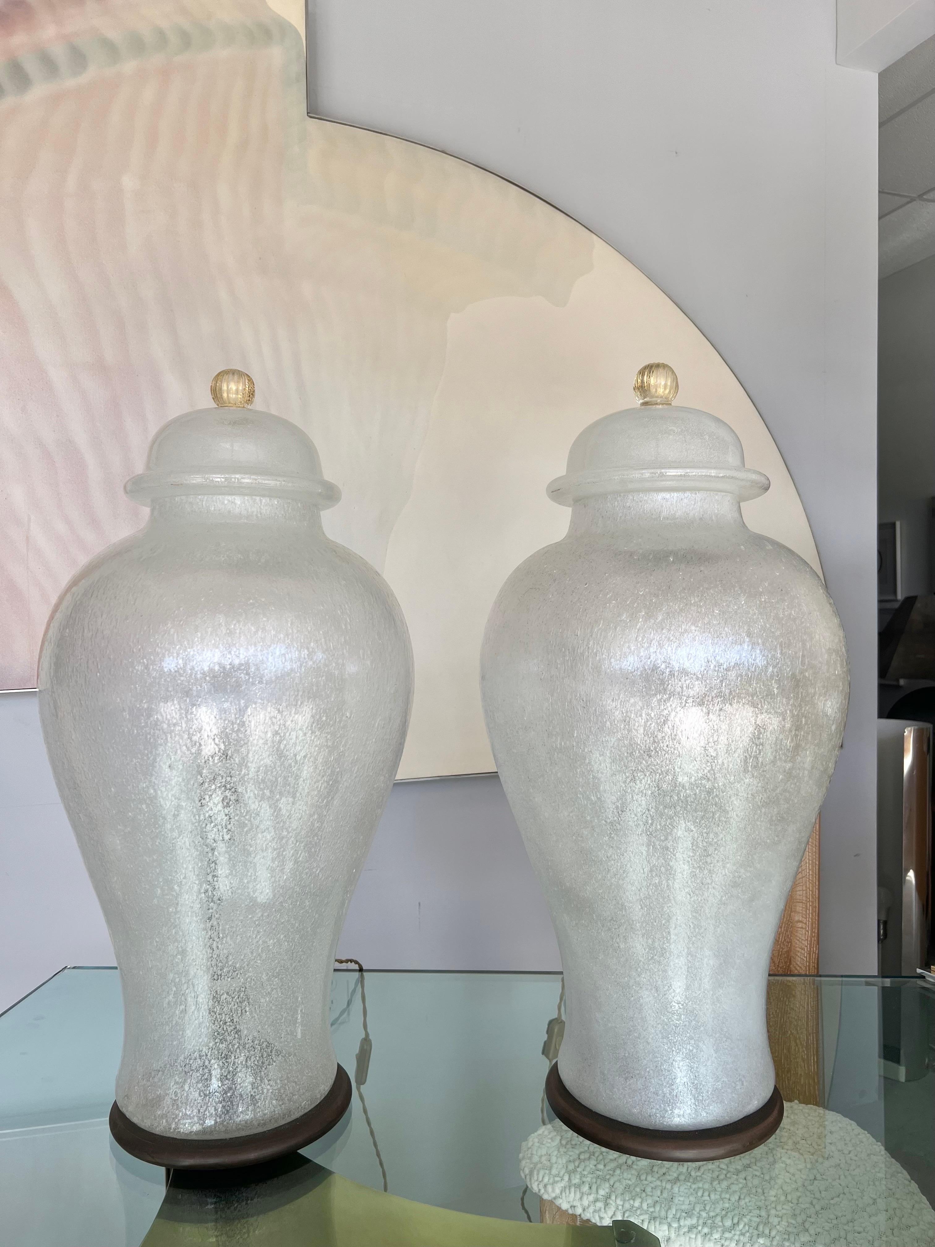 Monumental pair of lighted urns in pulegoso art glass by Seguso. The tops are removable exposing bronze fittings for 2 bulbs each. Round bronze bases, silk twist cords. Signed on the metal inside.
