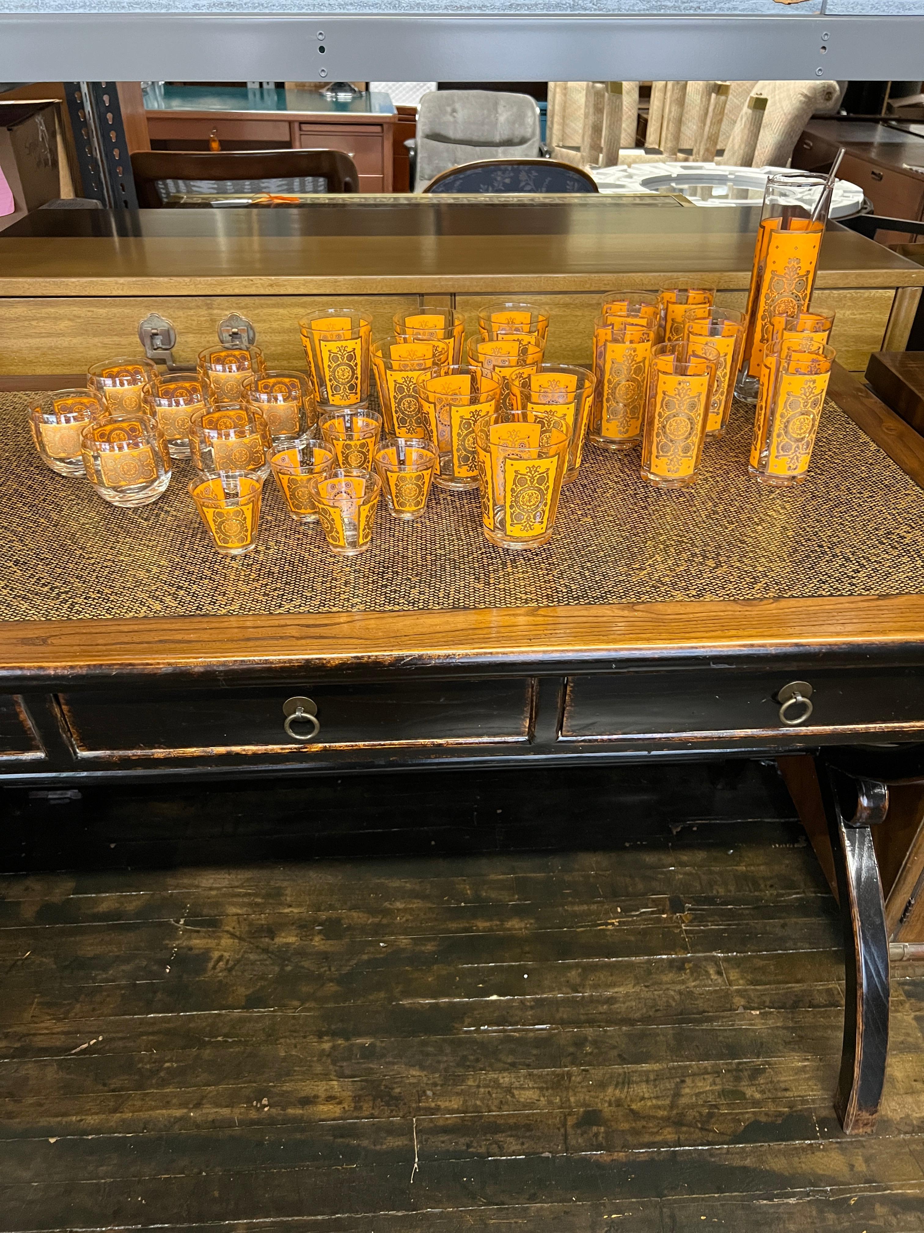 This is a monumental set of very rare mid-century barware designed by Irene Pasinski for Washington Glass.  This set features a design done in a bright orange and gold.  The gilding is almost entirely intact with very little loss (mostly on the