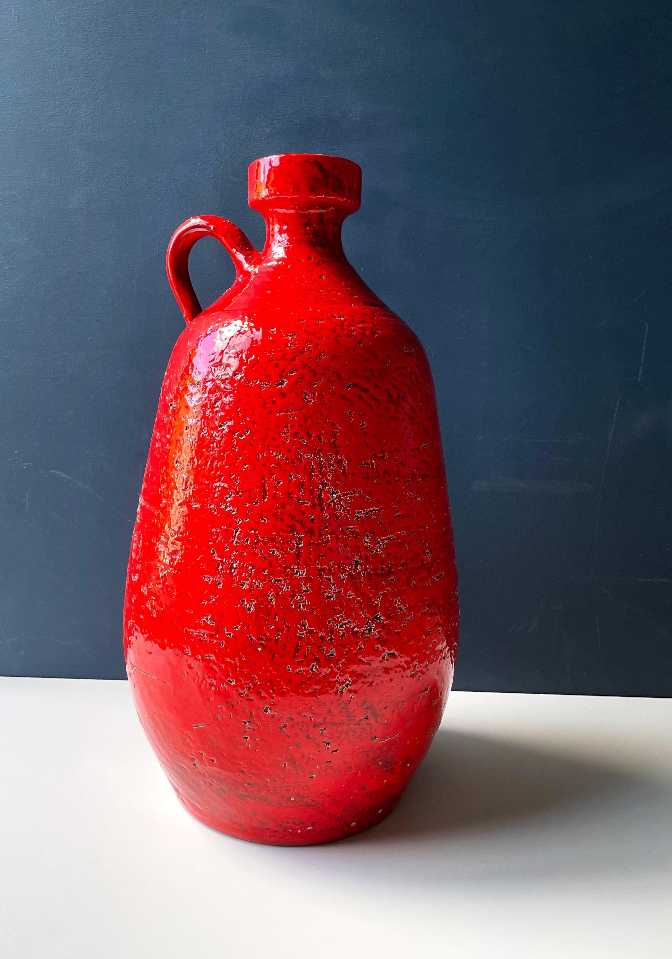 Vintage European monumental bottle pitcher shaped stoneware midcentury floor vase. Handcrafted in rustic chamotte clay with bright shiny red from top to bottom and black glaze on the inside with a small yellow glazed line separating the two colors.