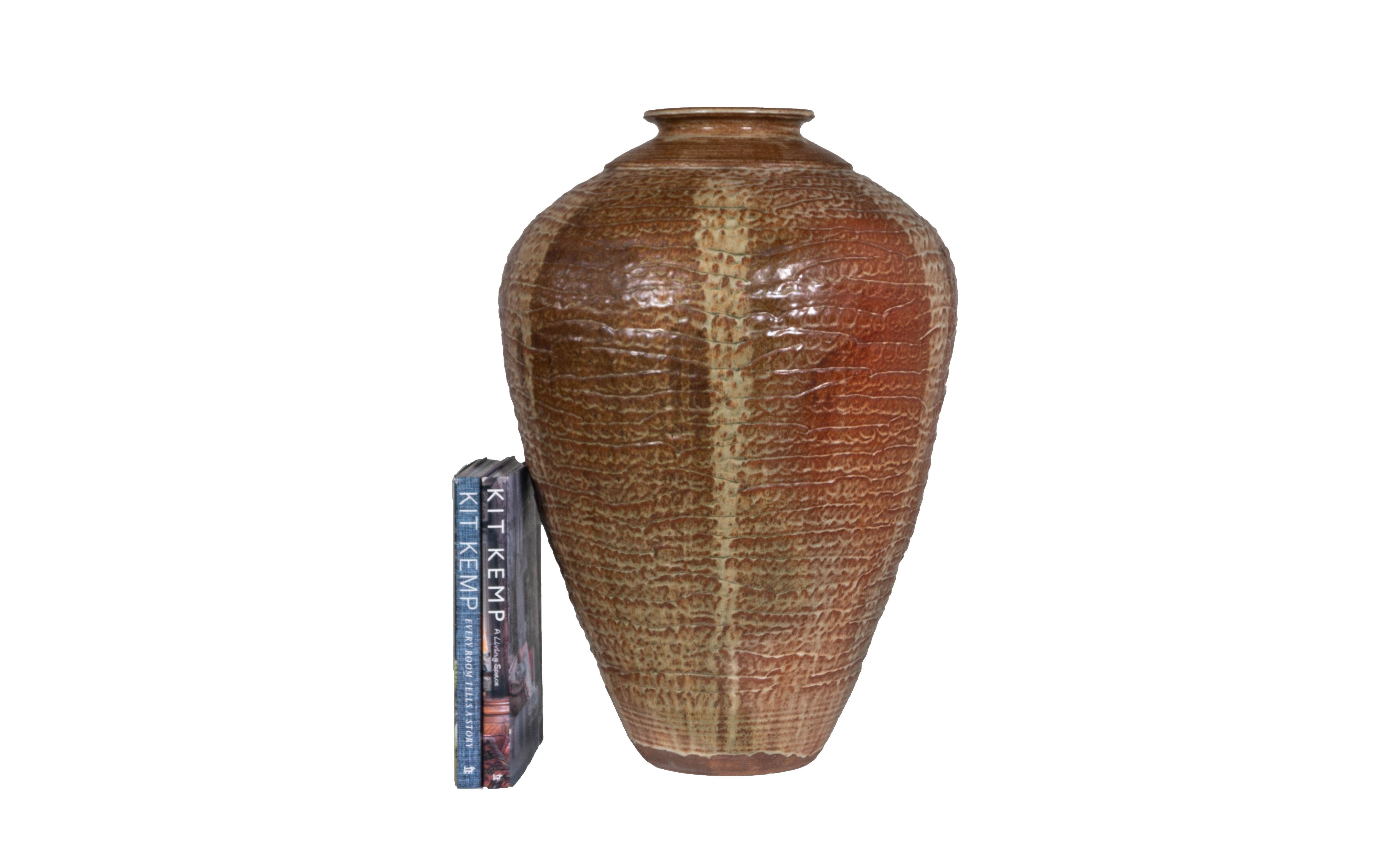 This monumental signed studio pot is truly something to behold. Its variegated tawny and sand colored glaze swirl together to create a one-of-a-kind work of art. Its ribbed texture is inviting to the touch and eye alike, the narrow opening of the