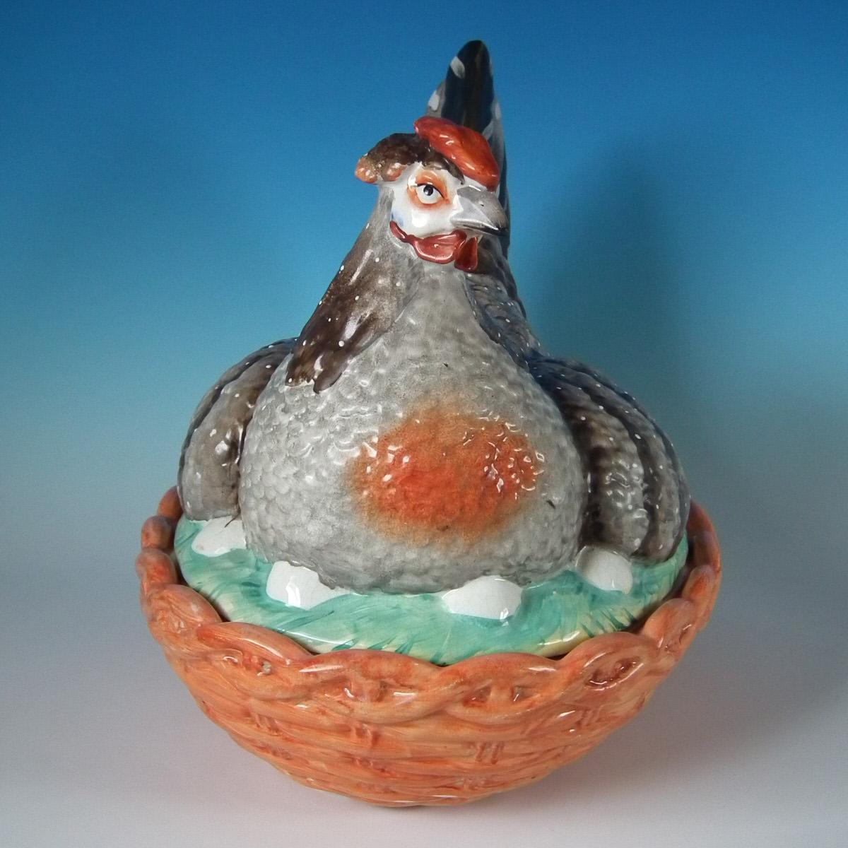 Staffordshire Pottery egg tureen and cover which features a hen sitting with her eggs, resting on a basketweave oval base. Decorated 'in the round' - decoration to front and reverse. Maker's marks painted to the underside. Very large size.