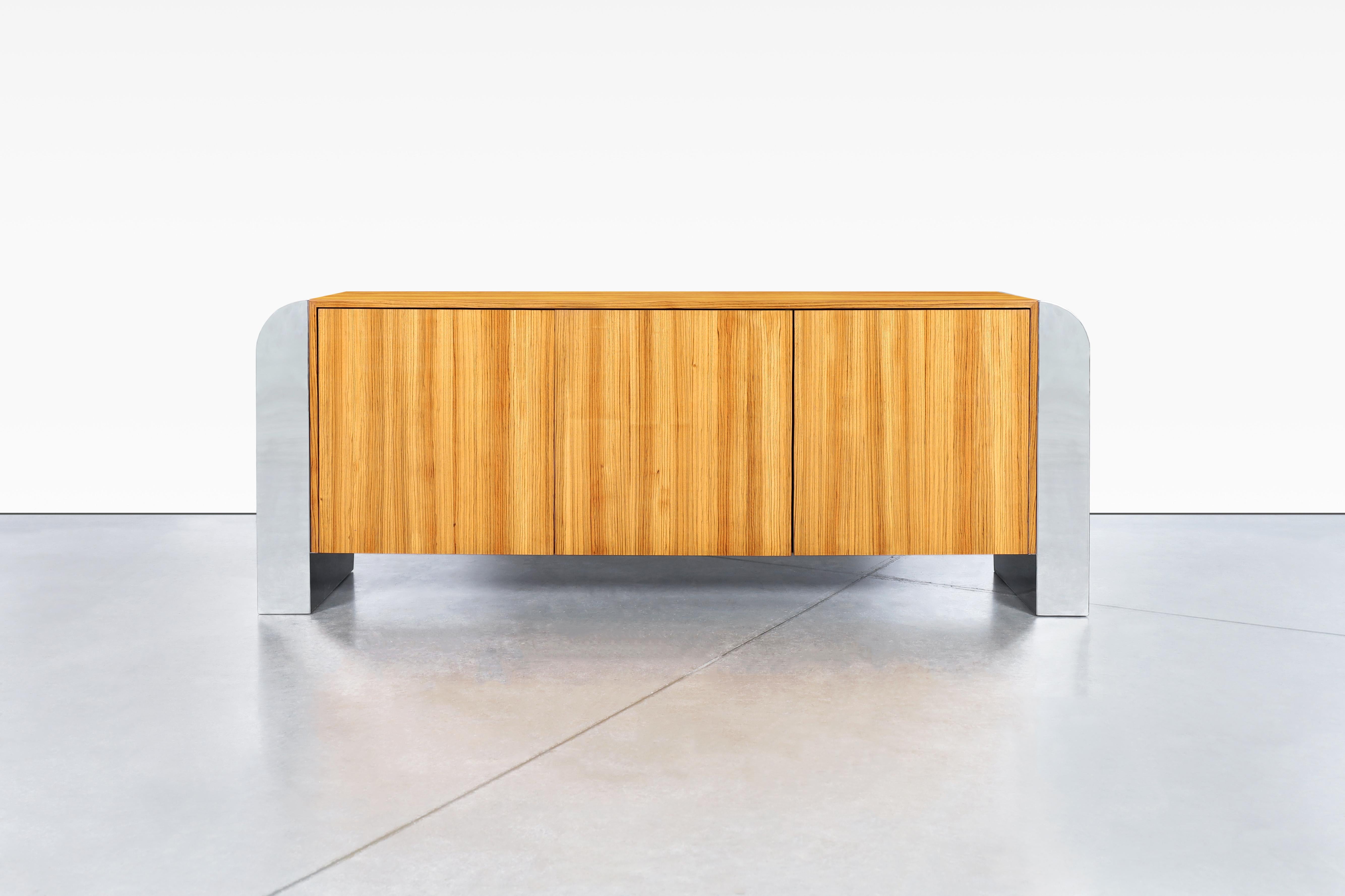This stunning credenza is a testament to the exquisite craftsmanship and unique design sensibility of John Mascheroni. The piece, which dates back to the 1970s, is crafted from exotic zebra wood sourced from central Africa, giving it a one-of-a-kind
