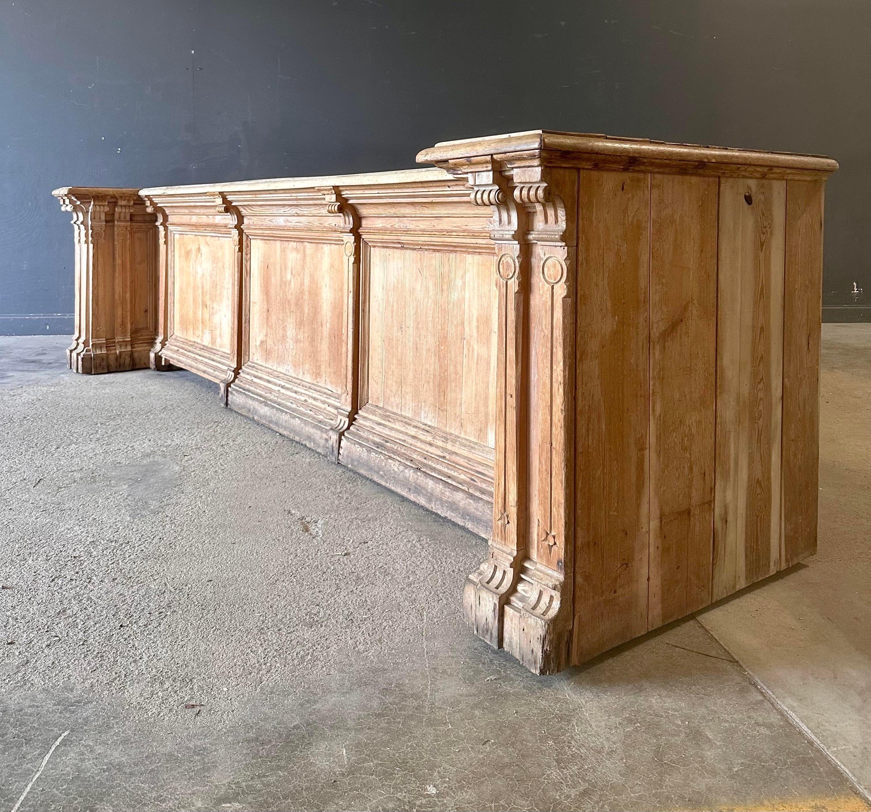 A monumental antique carved wooden bar, originally a store counter. Made of solid wood with carved columns. In the back is a lot of storage and several drawers. Truly a statement piece.