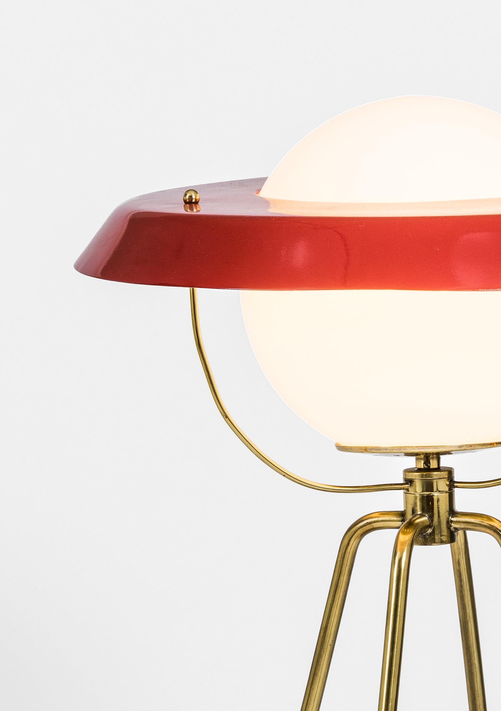A monumental table or sidebord lamp attributes to Luigi Caccia Dominioni. With all the characteristics of the designer : a disc-shaped lampshade in painted iron on an opaline glass globe, the curved brass tubes and terrazzo. 
The Italian's