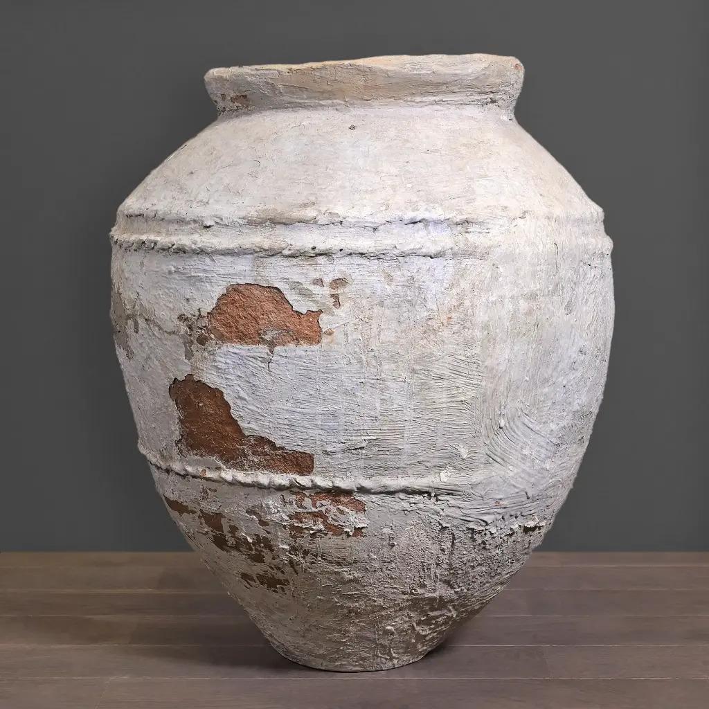 Questo monumentale vaso per l'acqua proveniente da Giava è un autentico recipiente in terracotta del XIX secolo, tradizionalmente utilizzato per conservare cibo o acqua potabile. Realizzato a mano e cotto a legna, presenta una superficie ricca di