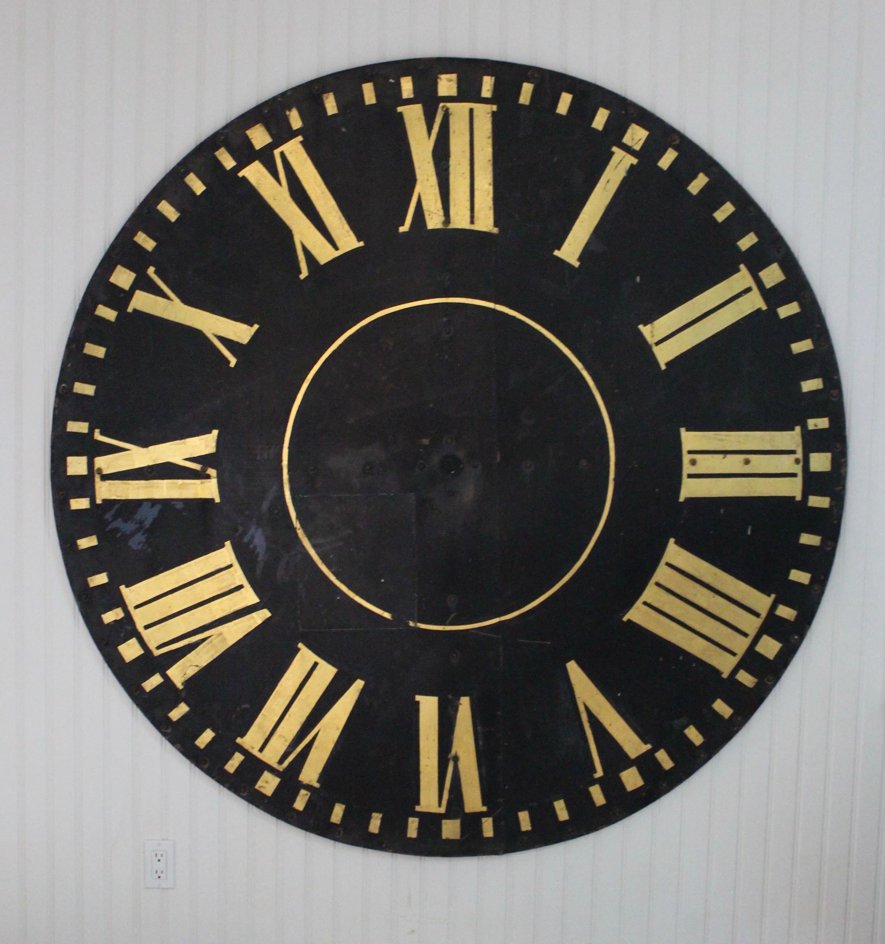 Monumental industrial tower clock face with gilded Roman numbers.