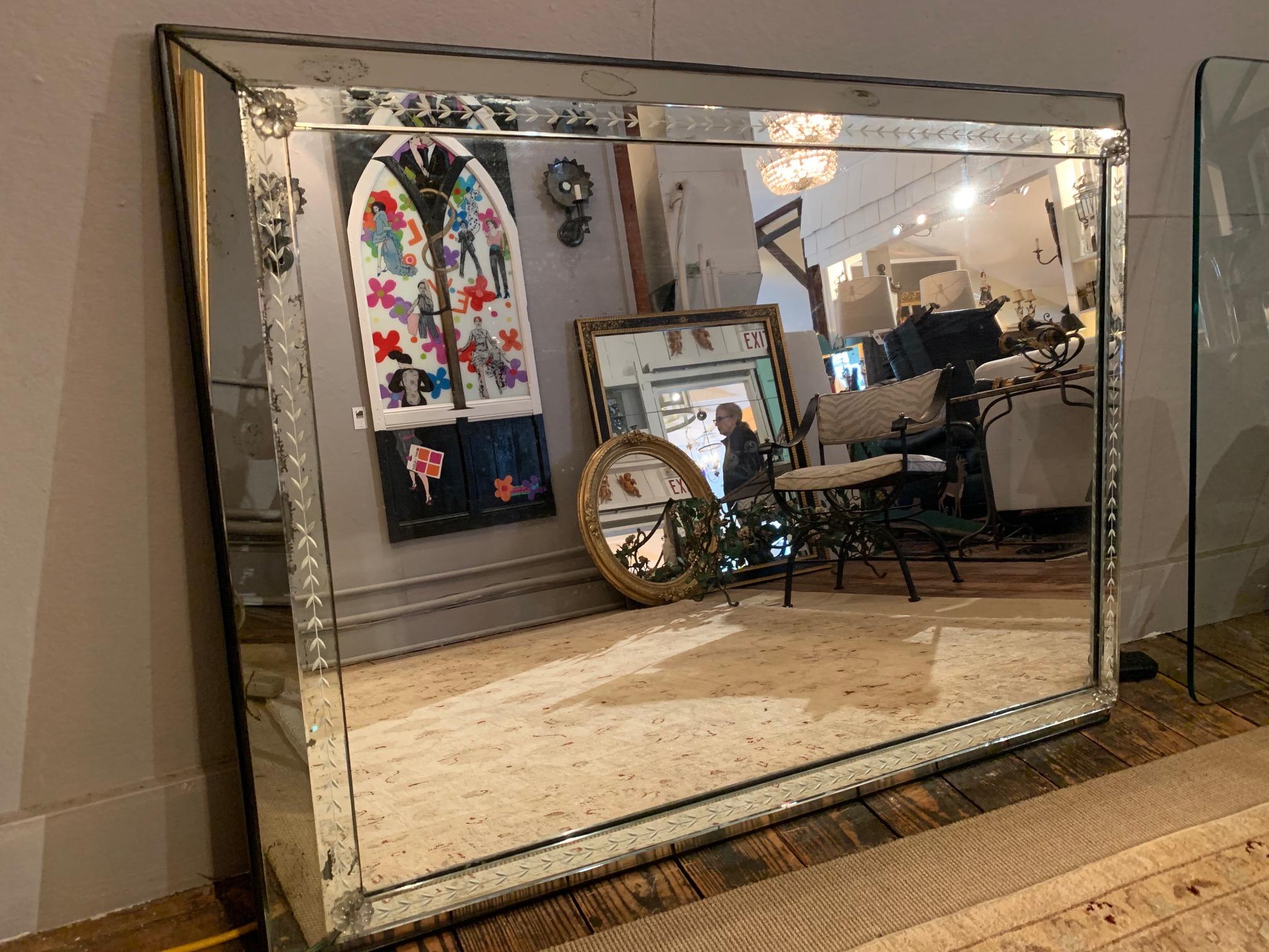 Very large impressive vintage art deco beveled mirror having etched decoration, glass decorative rosettes in each corner, and wonderful sculptural depth.