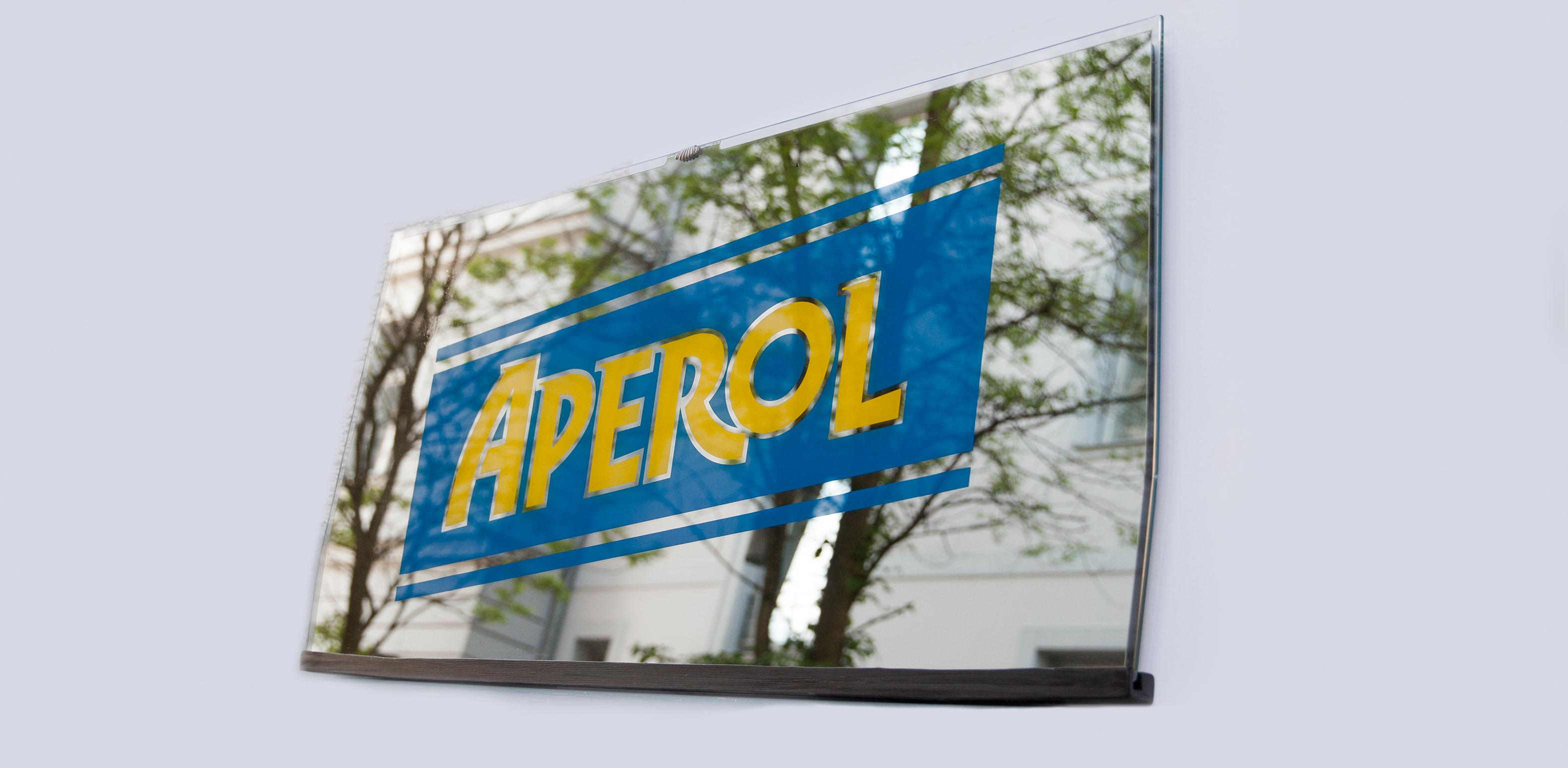 Original advertising old bar mirror of the famous liquor brand Aperol, Italy 1960s. The mirror is mounted on a wooden plate and has some decorative brass elements.