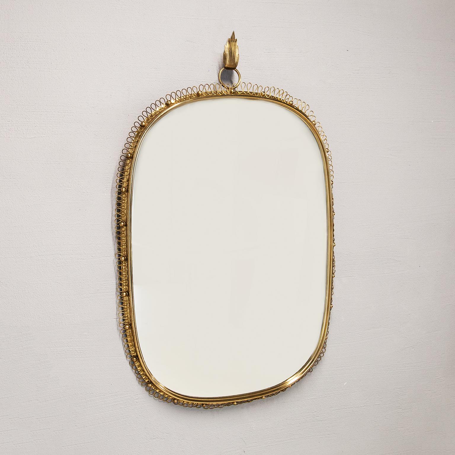 Huge wall mirror designed by Austrian Josef Frank and manufactured in Sweden by Svenskt Tenn in the 1960s.
The mirror is made of full shiny brass frame with spiral loop frame around and big round hanging hook on top. You can easily recognize his