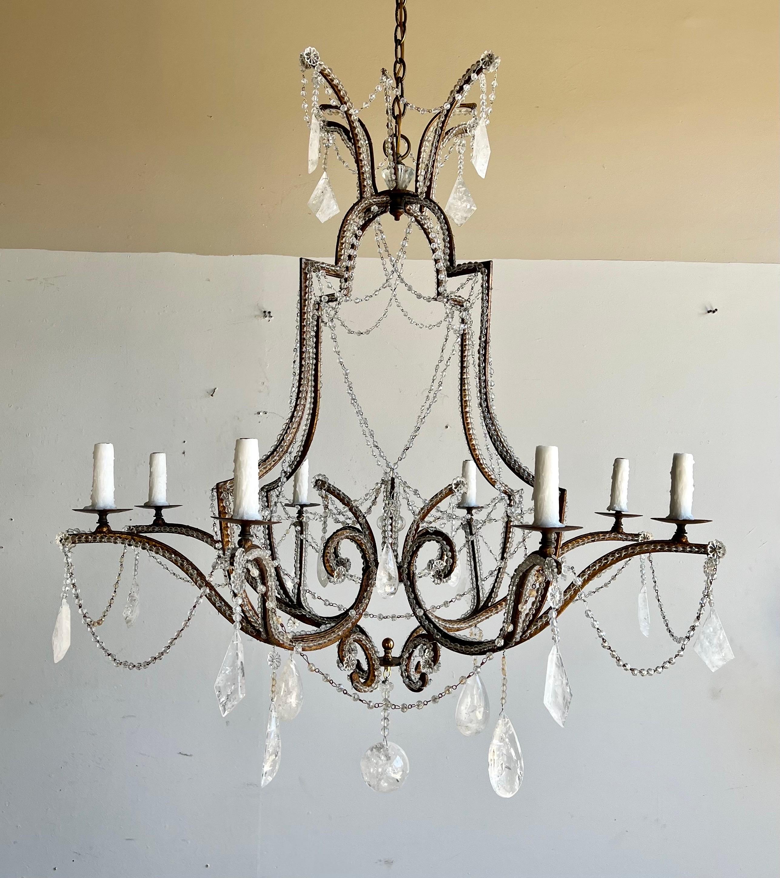 Monumental (10) light beaded wrought iron & rock crystal chandelier. The chandelier is adorned with garlands of beads and both almond & kite shaped rock crystals throughout. The chandelier is newly rewired with drip wax candle covers. Includes both