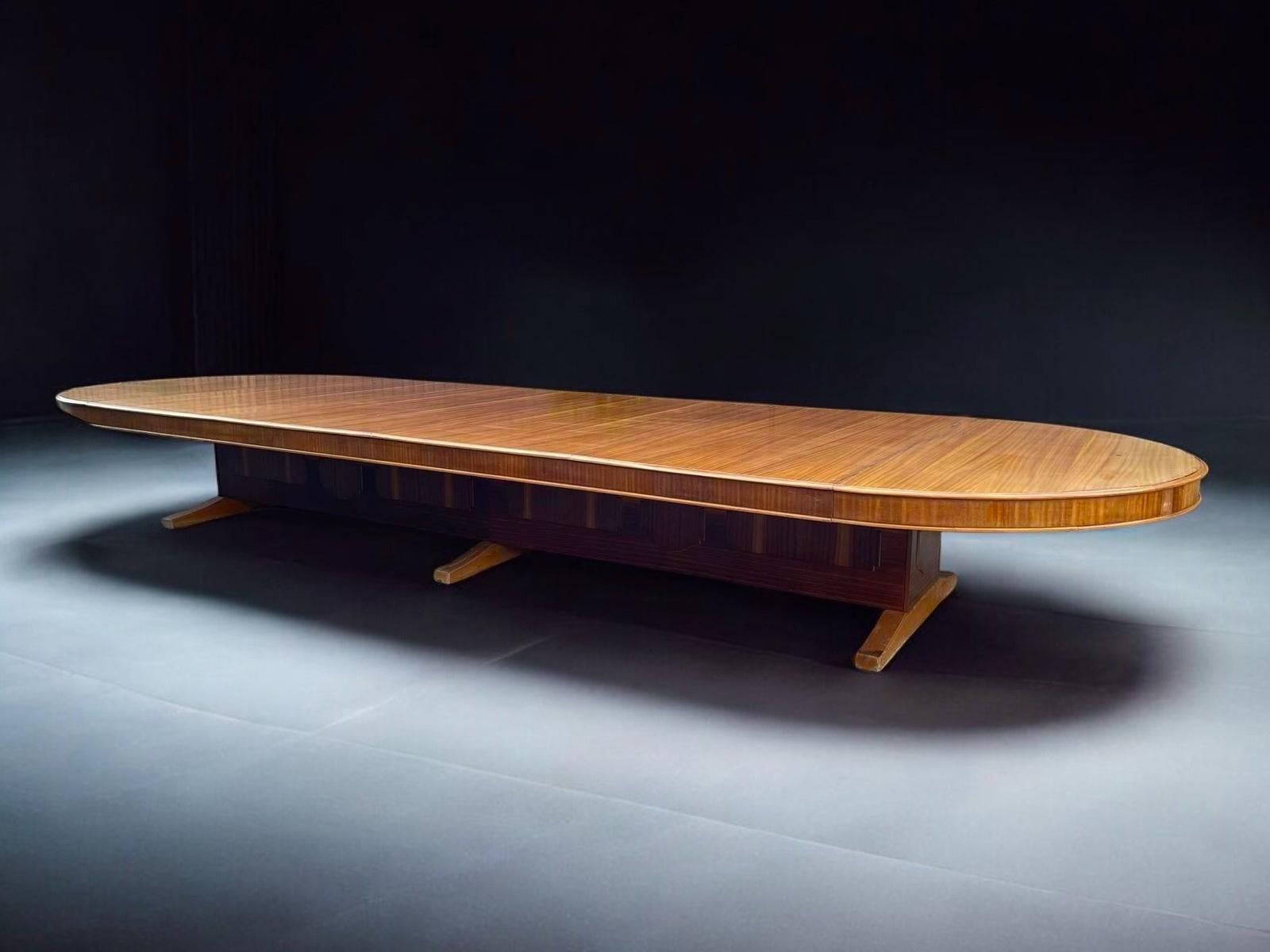 Table de réunion ou de conférence de taille monumentale,

Années 1960, construction en hêtre ou en bois tendre plaqué acajou sur des pieds à patins - ces derniers étant recouverts de panneaux plaqués, 

4 plateaux de table avec éléments