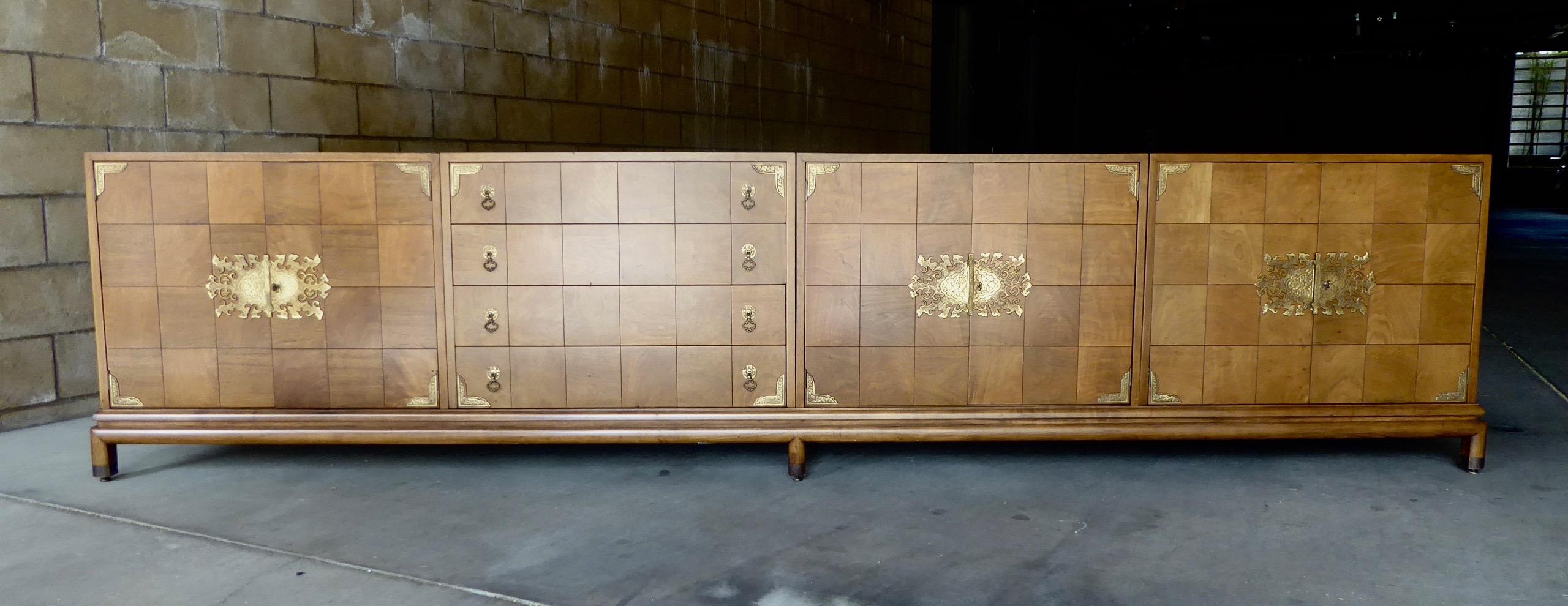 A monumental walnut credenza designed by Renzo Rutili for the Johnson Furniture Company, circa 1960. The credenza is composed of three separate cabinets and a single four-drawer chest, resting on an eleven foot long base and terminating in six