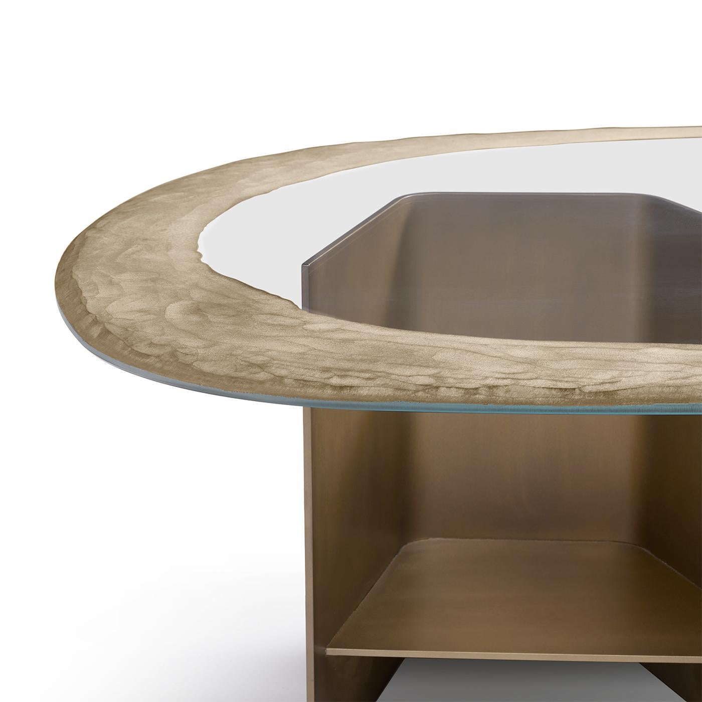 This coffee table epitomizes elegance, featuring a burnished brass metal structure and a top crafted from 15mm extra-clear glass. The meticulous detailing includes an engraved edge, treated with a diamond and silver grinding wheel, adding a touch of