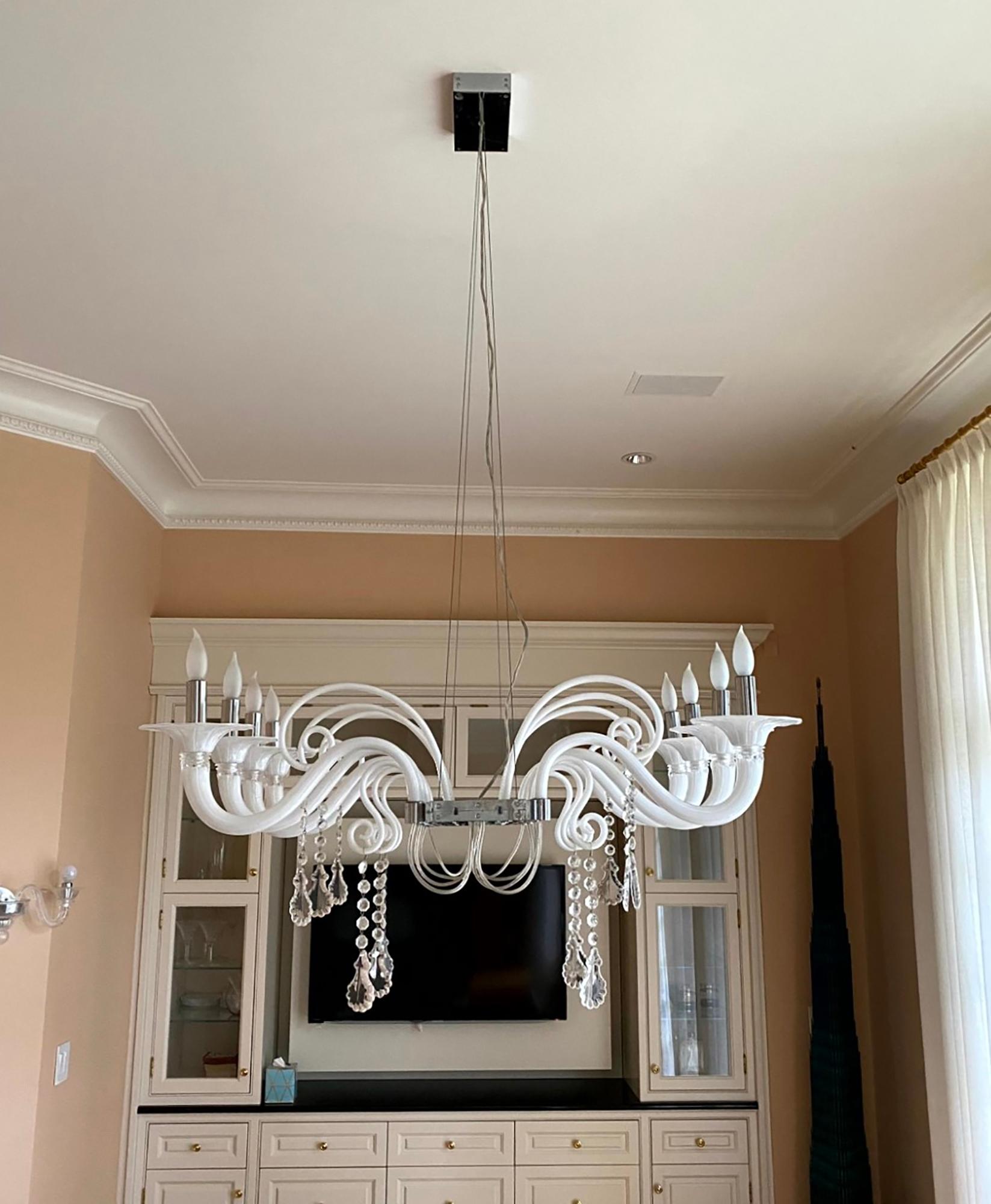 This unusual Contemporary chandelier, designed by Franco Raggi for Barovier & Toso, has eight white glass arms and stainless-steel hardware. It is draped with clear crystals on the bottom. This was retrieved from an estate located in Greenwich,