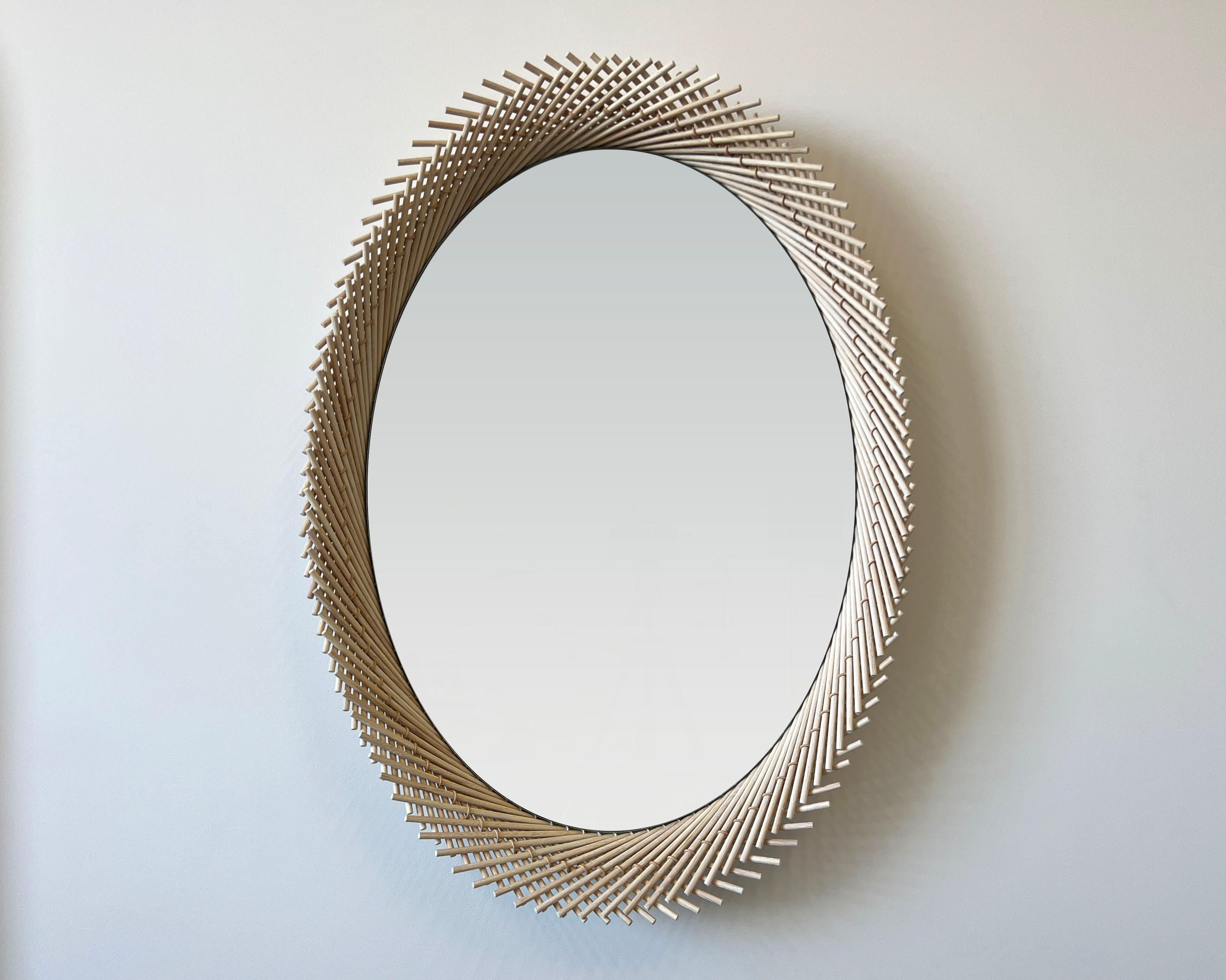 The Oval Mirror pushes the strict geometry that occurs as a result of stitching the dowels together to create a dynamic edge. Each layer of the Mooda rises and falls inversely to the other as they travel along the circumference of the mirror, giving