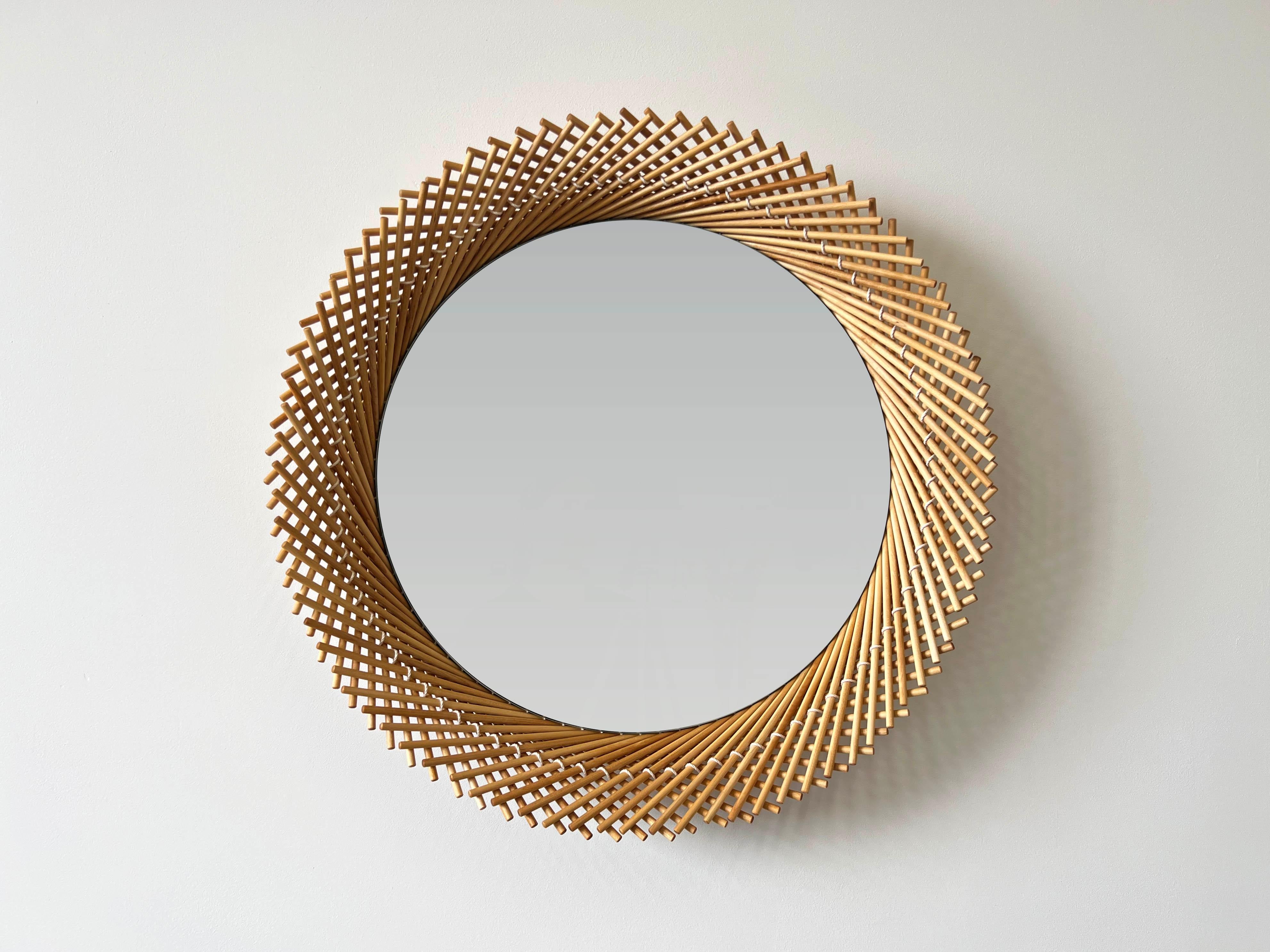 The Mooda Mirror is composed of a set of dowels stitched together to create a beautiful geometric edge around the glass. The mirror in turn reflects the dowels along its circumference, completing the traditional form of the Mooda. 

Available in two
