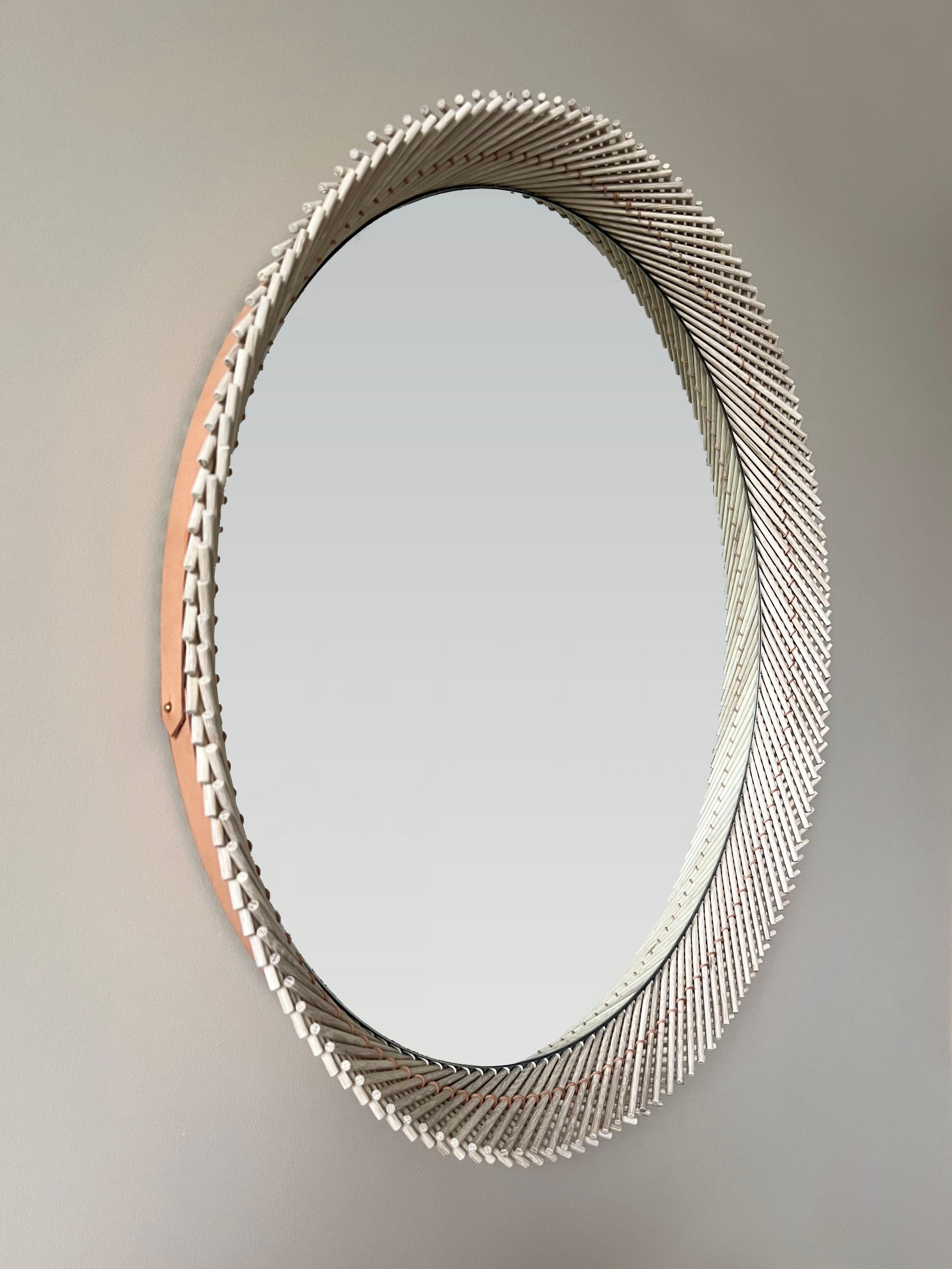The Mooda Mirror is composed of a set of dowels stitched together to create a beautiful geometric edge around the glass. The mirror in turn reflects the dowels along its circumference, completing the traditional form of the Mooda. 

Available in two