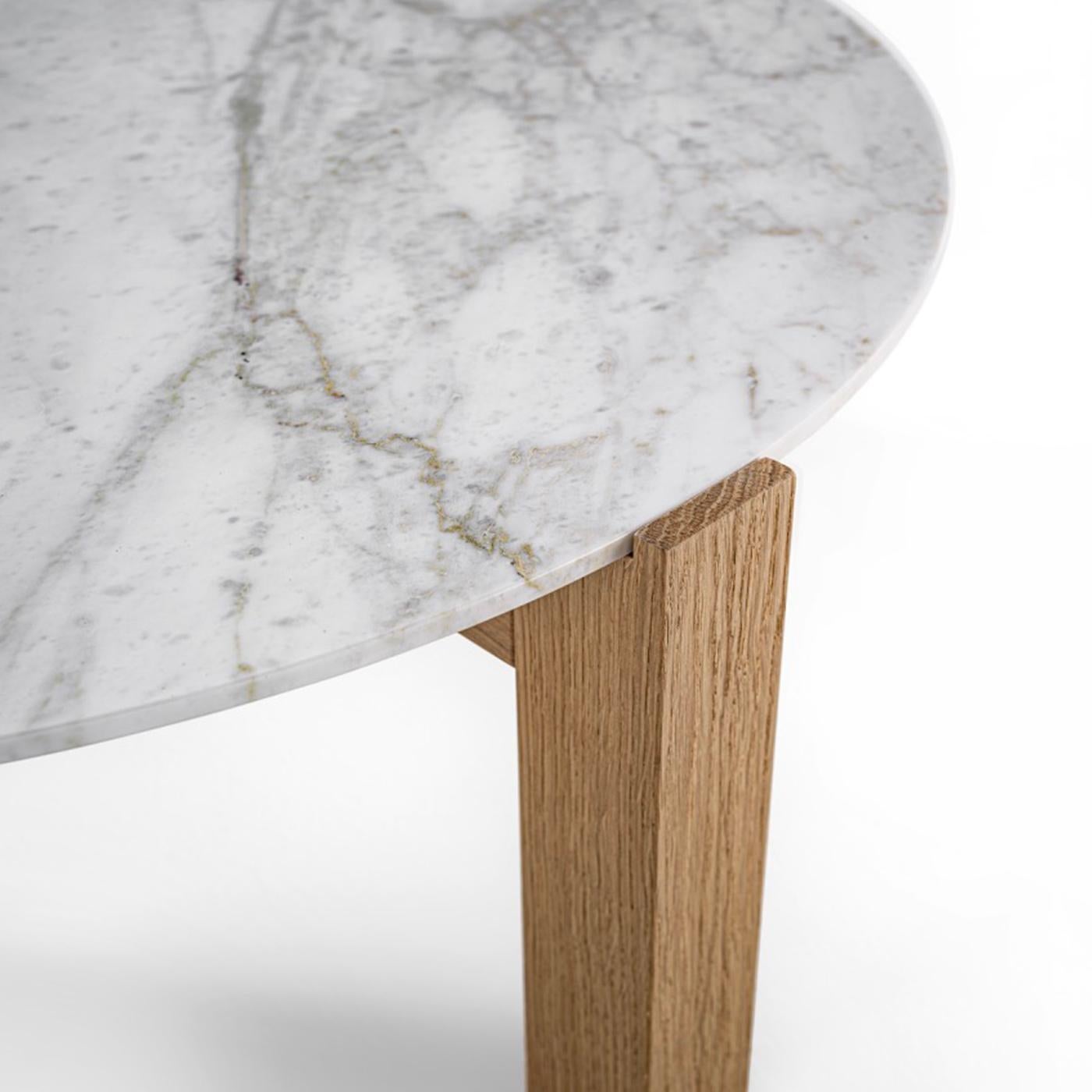 A showcase of unpredictable, intriguing natural traceries represents the spontaneous decoration of this stunning coffee table. A sturdy base in solid wood consisting of rigorously-sculpted legs welcomes the superb circular white marble top in