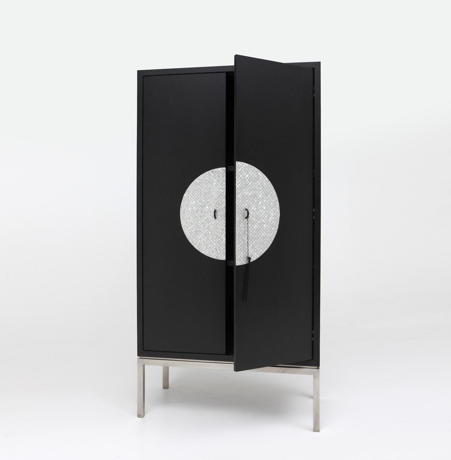 The Moon cabinet is crafted in painted MDF with a circular pattern in mother of pearl. This cabinet sits with carefully balanced proportion on a natural steel frame.