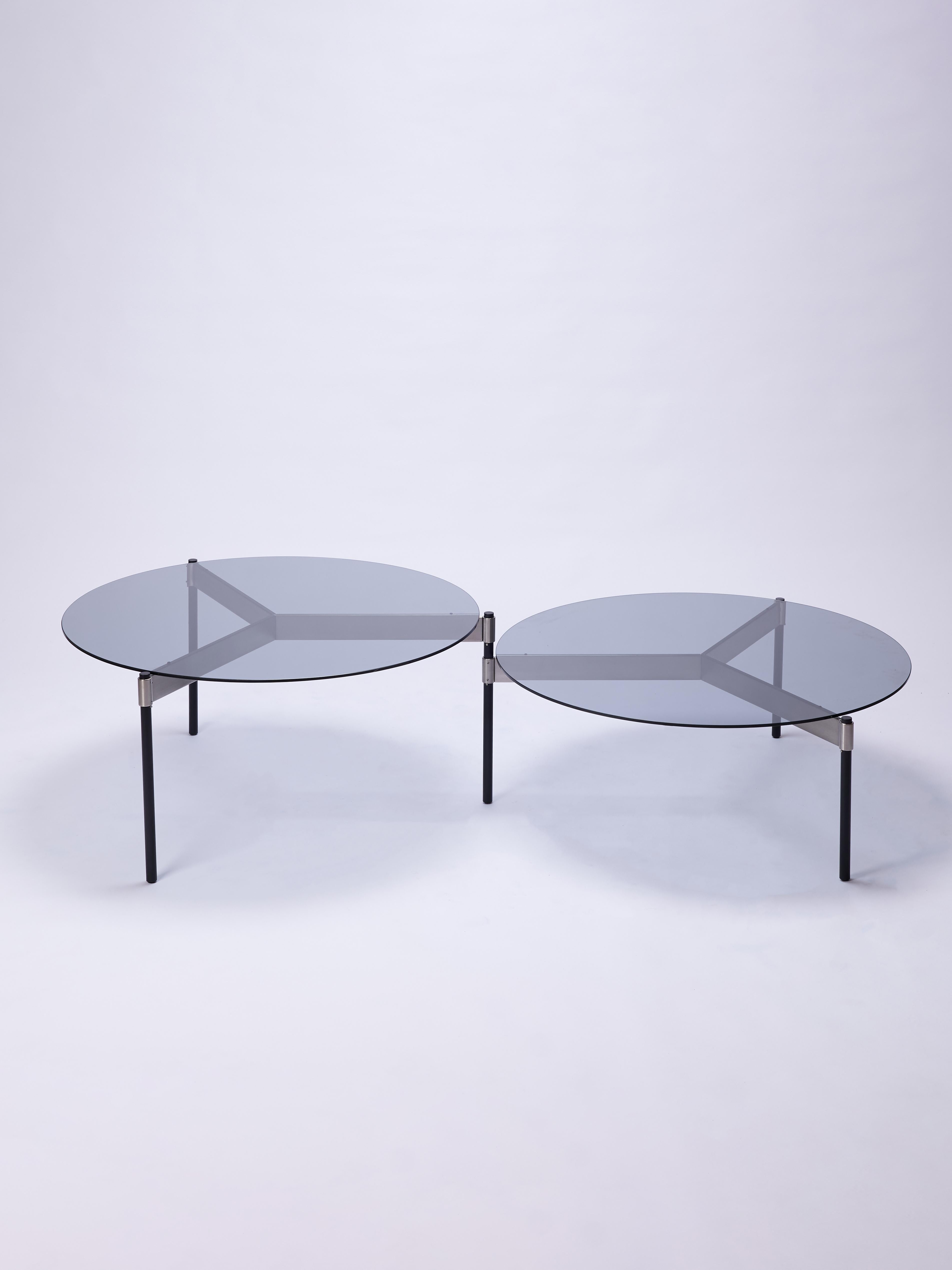 Moon is a single coffee table conformed by three round tops, which by rotating on the axis of the leg they share with its adjacent top, allows different configurations to be formed.

This version of the table features smoked glass tops,