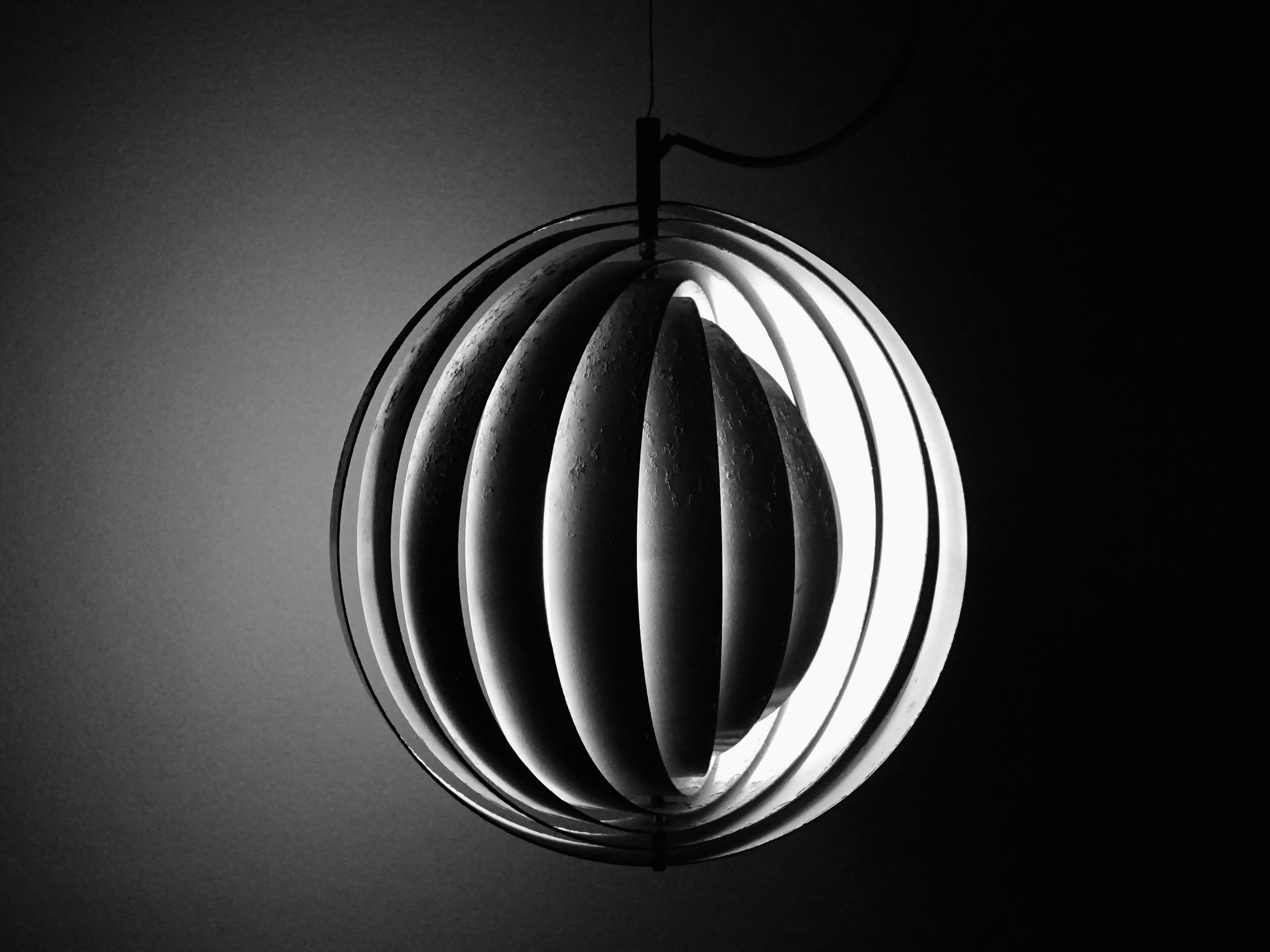 La lampada è composta da un gran numero di dischi bianchi laccati a forma di anello, sospesi intorno alla lampadina centrale. I dischi a forma di ventaglio nascondono la lampadina e allo stesso tempo fungono da riflettori, attraverso i quali viene