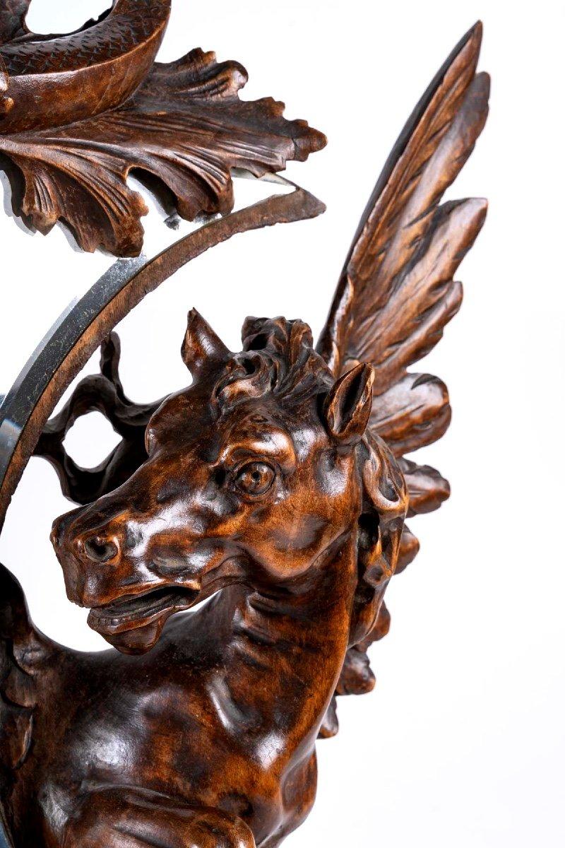 Lovely table mirror in the shape of a bevelled crescent moon, around which wraps a magnificent wooden sculpture, with rounded and muscular shapes, representing Pegasus, wings spread, defender and protector of this very beautiful moon, looking
