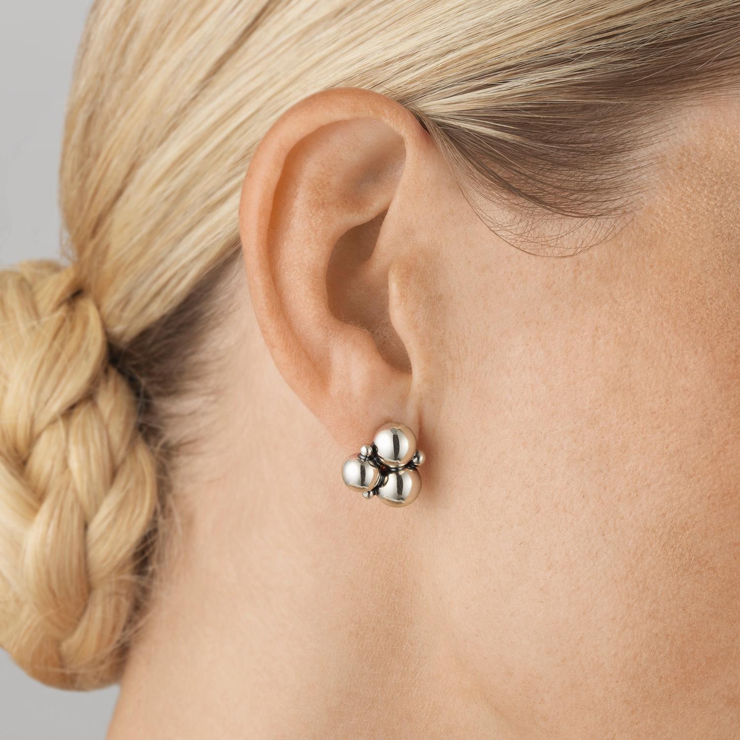 An abstract bunch of grapes made from sterling silver beads forms this pair of bold ear studs. Referencing the natural forms seen in the highly decorative Art Nouveau period and featuring an oxidised finish that accentuates their sculptural shape,