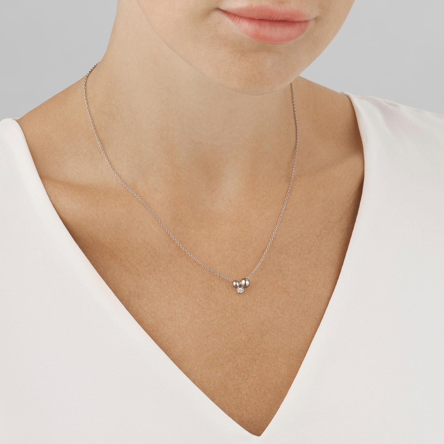 Understated and elegant, this beautiful pendant is formed from two sterling silver beads clustered together with a single brilliant cut diamond and suspended from a fine chain. Contemporary in design, the pendant has a classical sophistication that