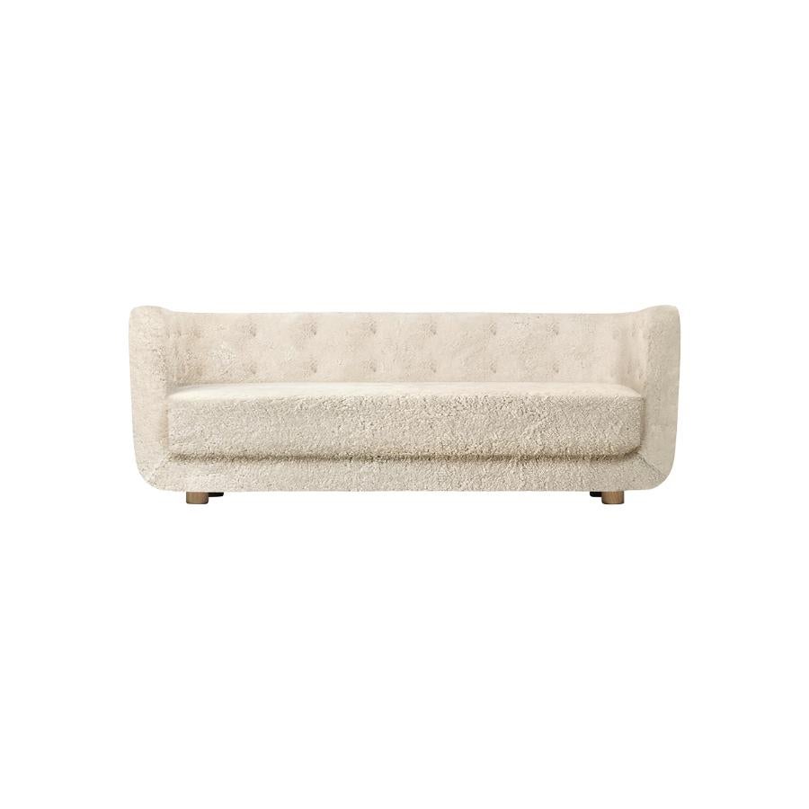 Moonlight sheepskin and smoked oak vilhelm sofa by Lassen.
Dimensions: W 217 x D 88 x H 80 cm. 
Materials: Sheepskin, Oak.

Vilhelm is a beautiful padded three-seater sofa designed by Flemming Lassen in 1935. A sofa must be able to function in