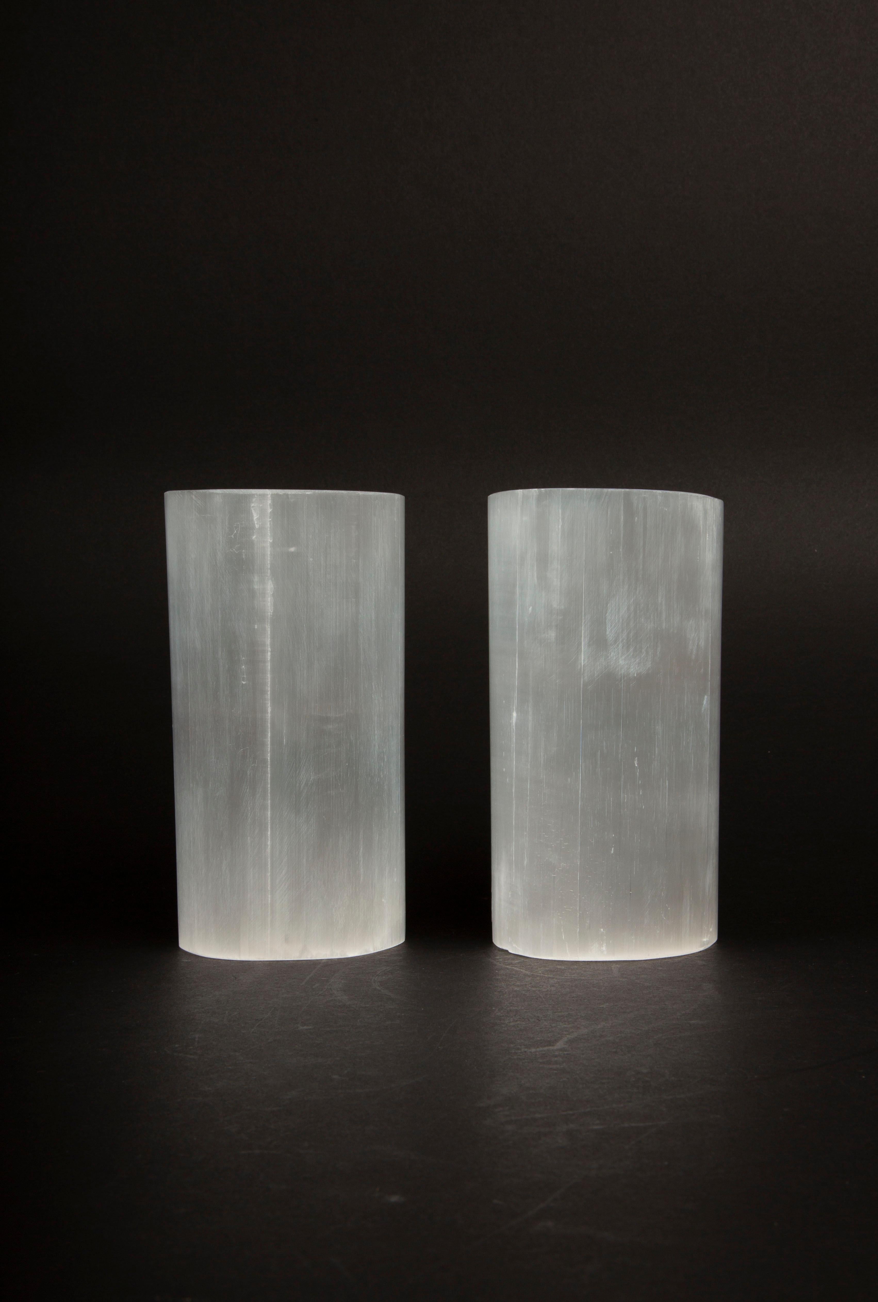 This pair of luminous selenite votive holders is a captivating addition to any space, designed to hold standard tea light candles. Carved from a pearly variety of gypsum, these pieces are named after Selene, the Greek goddess of the moon, reflecting