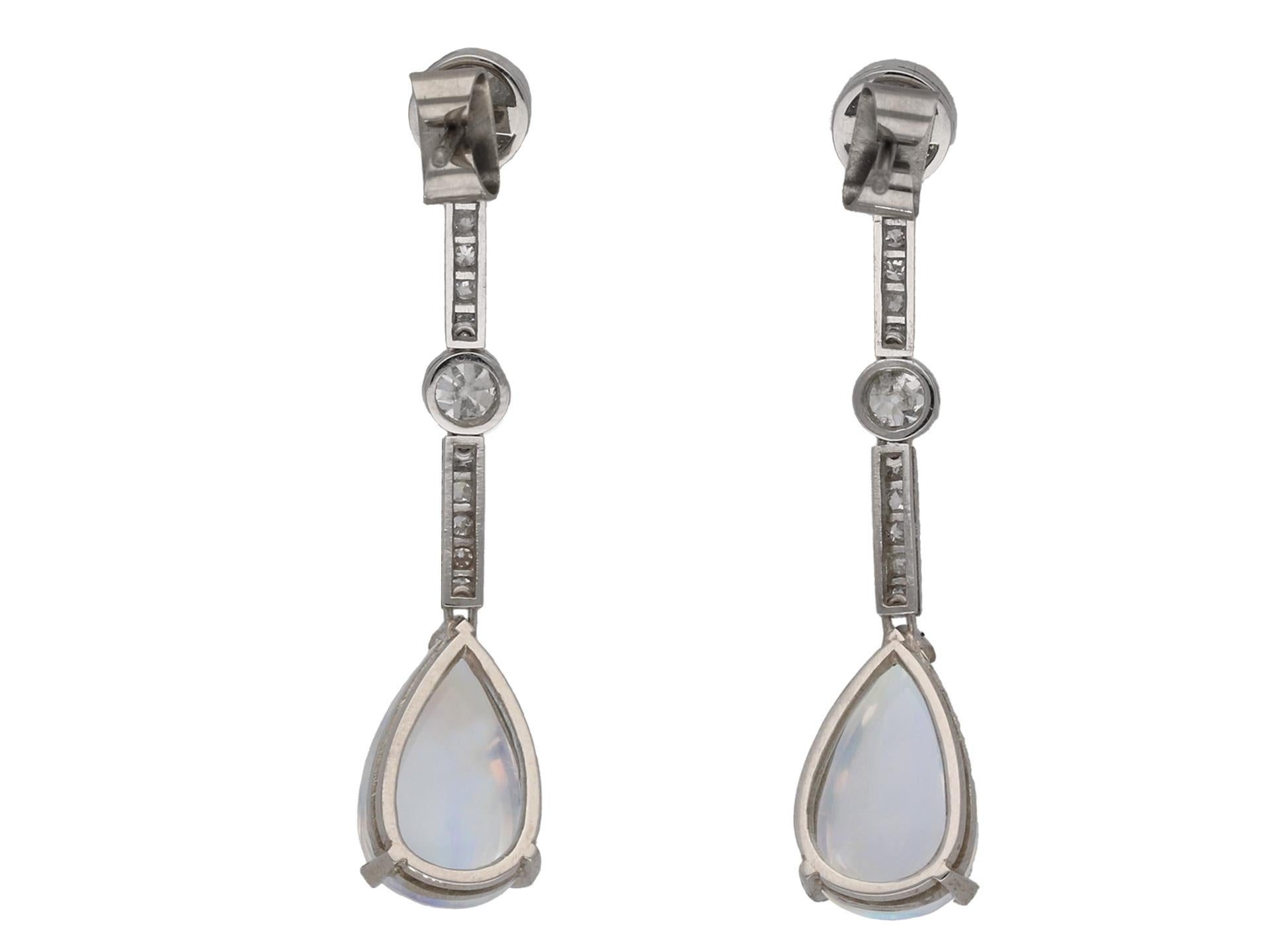 Moonstone and diamond drop earrings. A matching pair, each set with one drop shape cabochon natural moonstone in an open back claw setting, two in total with a combined approximate weight of 12.00 carats, set to top with one round old cut diamond in