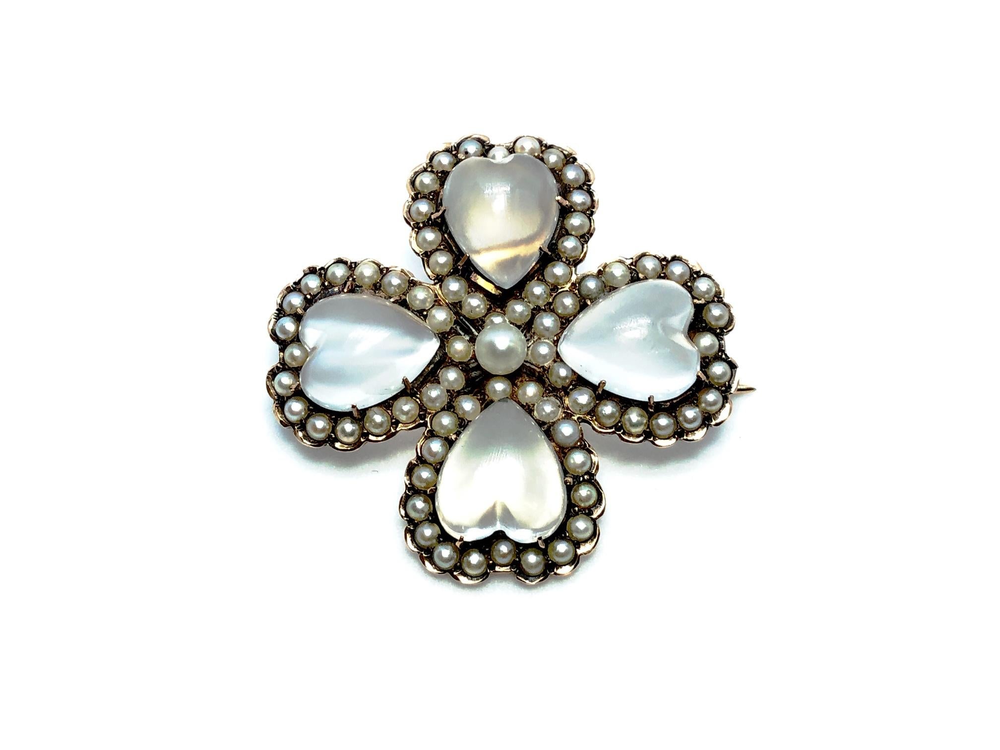 An antique moonstone and pearl four leaf clover brooch-cum-pendant, with four heart shape moonstones, surrounded by natural half seed pearls, with a natural pearl in the centre, mounted in 14ct gold. engraved Mary Ellison June. 15 '90.