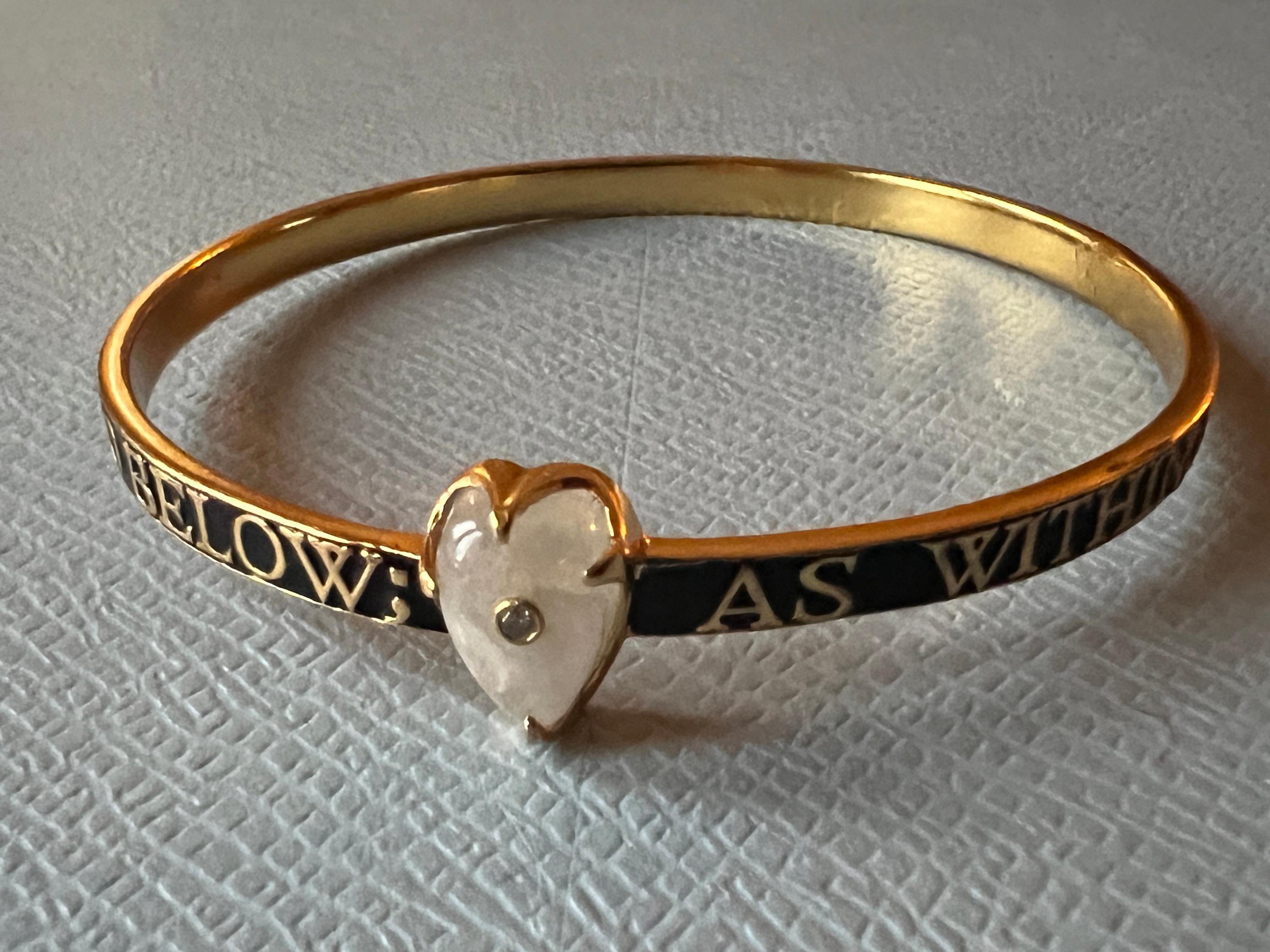 Bangle smaltato nero con cuore in pietra di luna e diamante  

Bracciale con diamante e pietra di luna a cuore Smalto nero Stile vittoriano Hermetica 

Si ispira ai concetti ermetici e cabalistici del micro e macro cosmo. 

Ottone placcato oro con