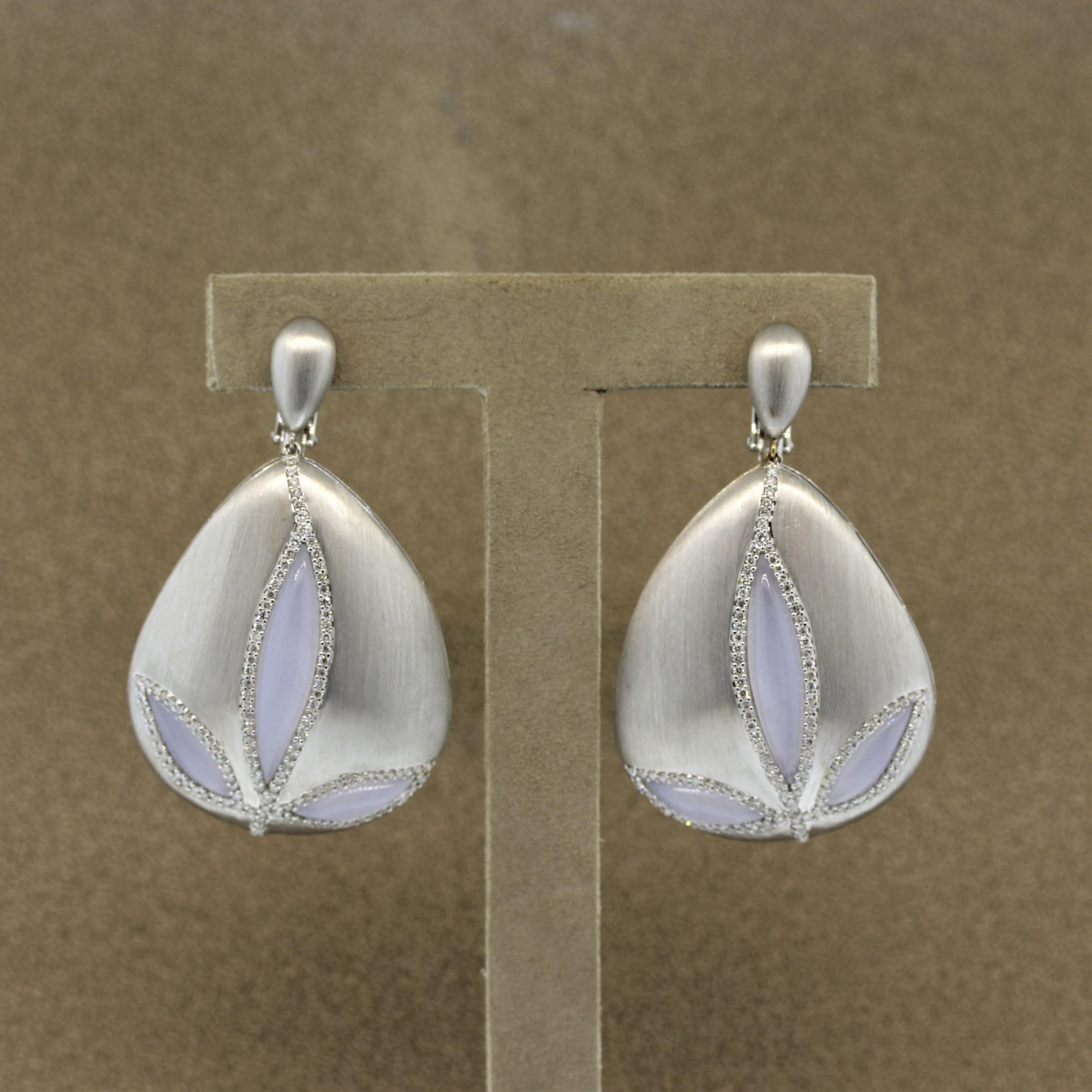 A sweet pair of earrings designed to resemble a flower. They feature 6 pieces of hand carved moonstone weighing a total of 9.46 carats, which are haloed by 1.86 carats of round brilliant cut diamonds. The earrings are made in 18k white gold which