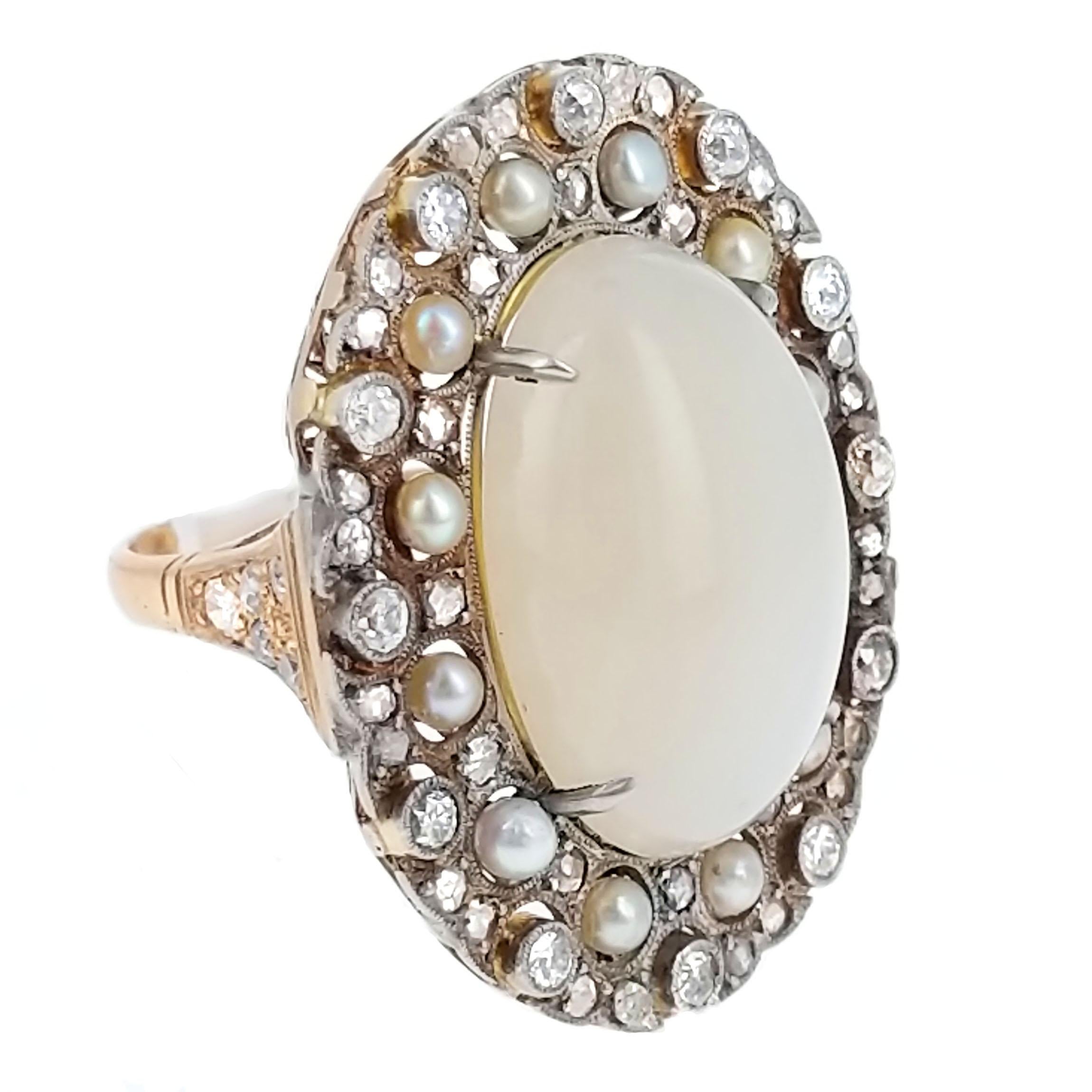 Of oval shape, centering a cabochon-cut moonstone of cream color, in a surround of rose- and european- cut diamonds and seed pearls.
Mounted in platinum and yellow gold. Size 7.75.

A very unique cocktail ring. The oval frame and basket is early