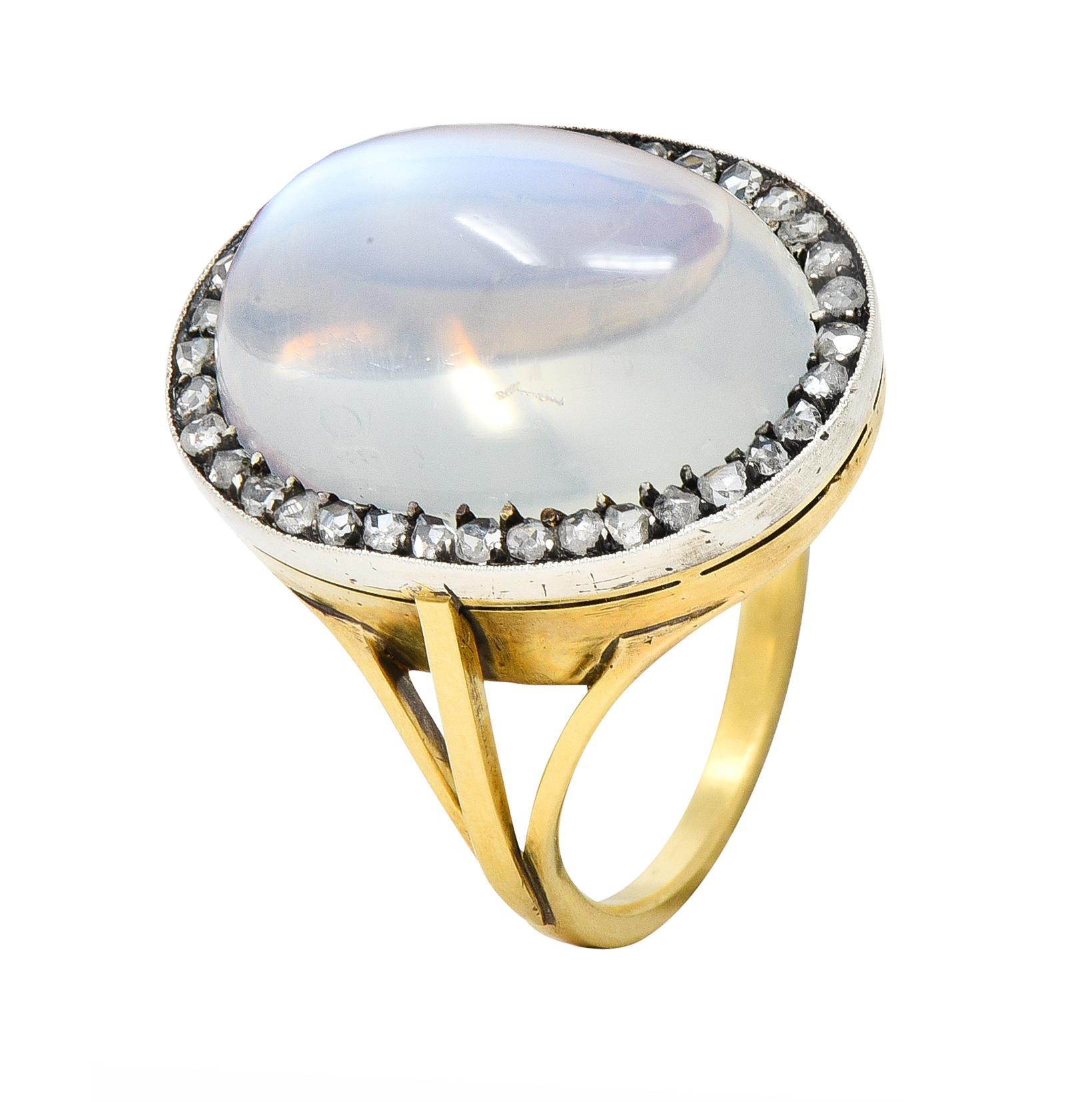 Centering an oval-shaped moonstone cabochon measuring 11.5 x 17.0 mm 
Translucent colorless body with vivid blue adularescence 
Prong set in silver with a halo surround of rose cut diamonds 
Bead set and weighing approximately 0.36 carat total