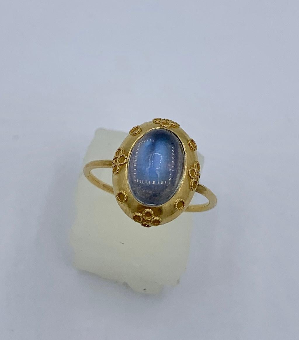 This is a stunning antique 19th Century Moonstone Etruscan Revival ring.  The Etruscan Archeological Revival ring features a magnificent oval Moonstone cabochon of gorgeous color and luminescence.  It is set in a 10 Karat Gold design with exquisite