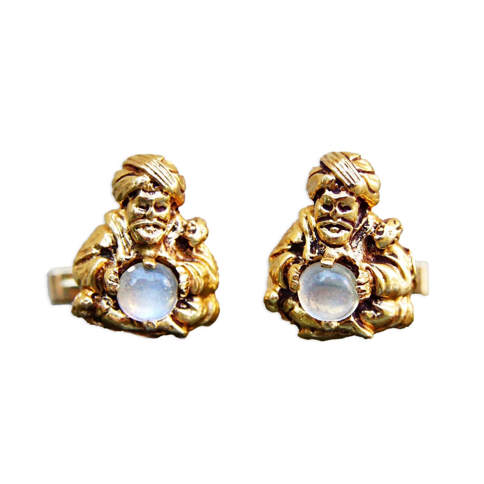 An amazing pair of 14k moonstone fortune teller cufflinks. Each cufflink features a small yellow gold psychic figure holding a round moonstone cabochon. The crystal gazer is incredibly detailed and even has a small snake wrapped its shoulder. The
