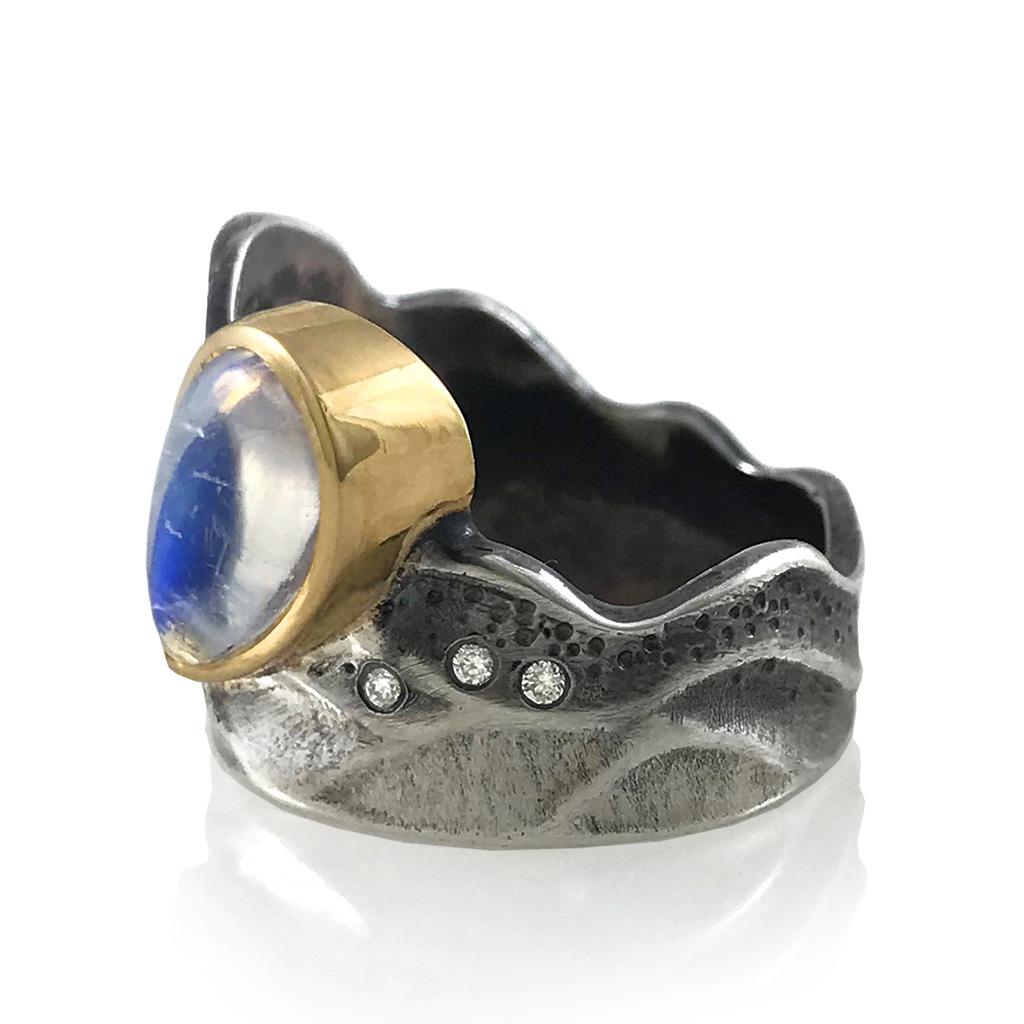 La bague contemporaine Moonlight Ring de K.Mita brille dans le ciel sombre. Réalisé à la main par l'artiste en or jaune 18 carats et en argent sterling oxydé, il est orné d'une pierre de lune de 2,40 carats et de diamants de 0,07 carat. Autour de la