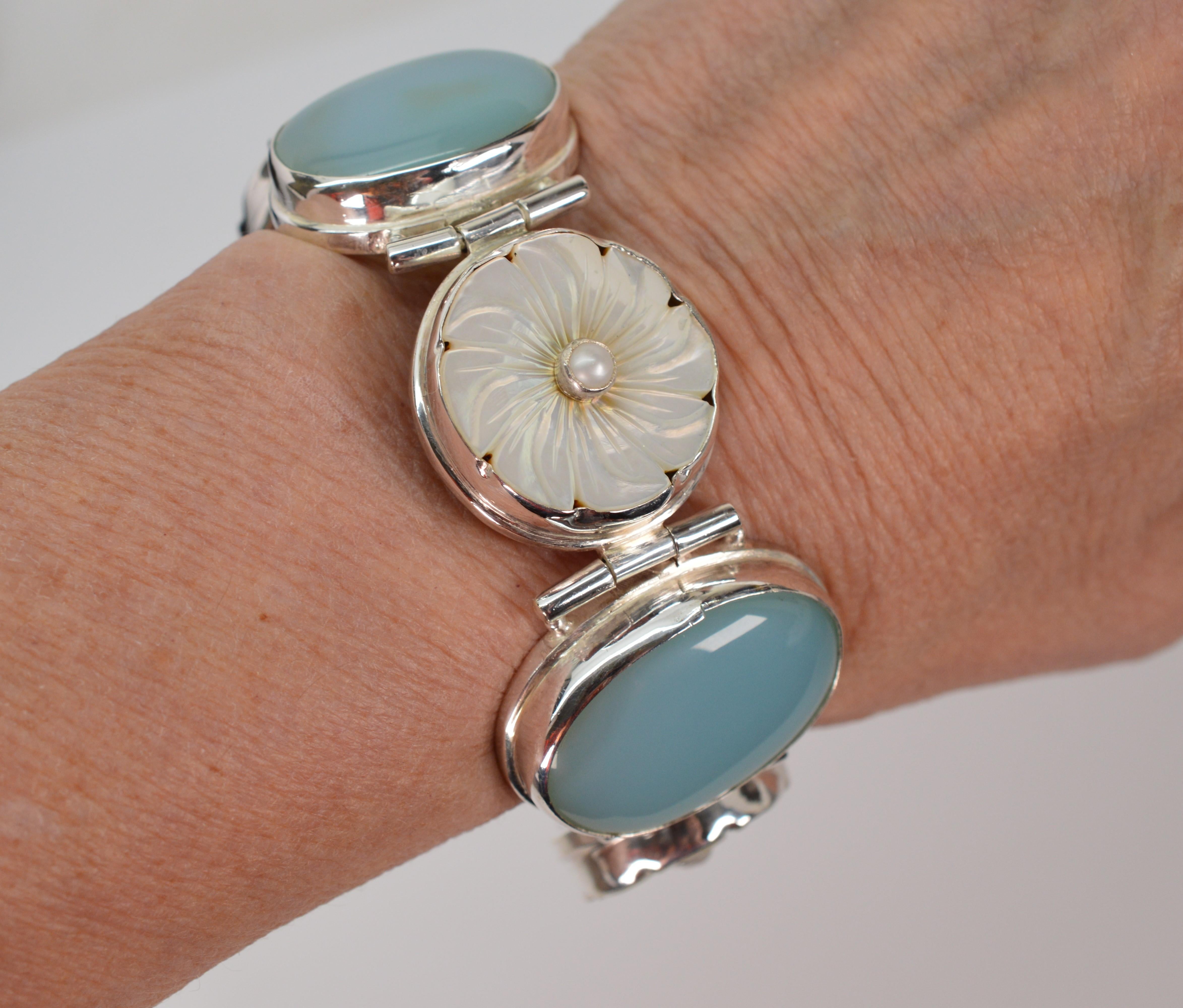 Soft nurturing hues of sage and blue lure the eye on this striking vintage bracelet as it presents three large and highly polished oval moonstone cabochons, each measuring 21 x 30mm, that are bezel set in sterling silver. Alternating along the
8+
