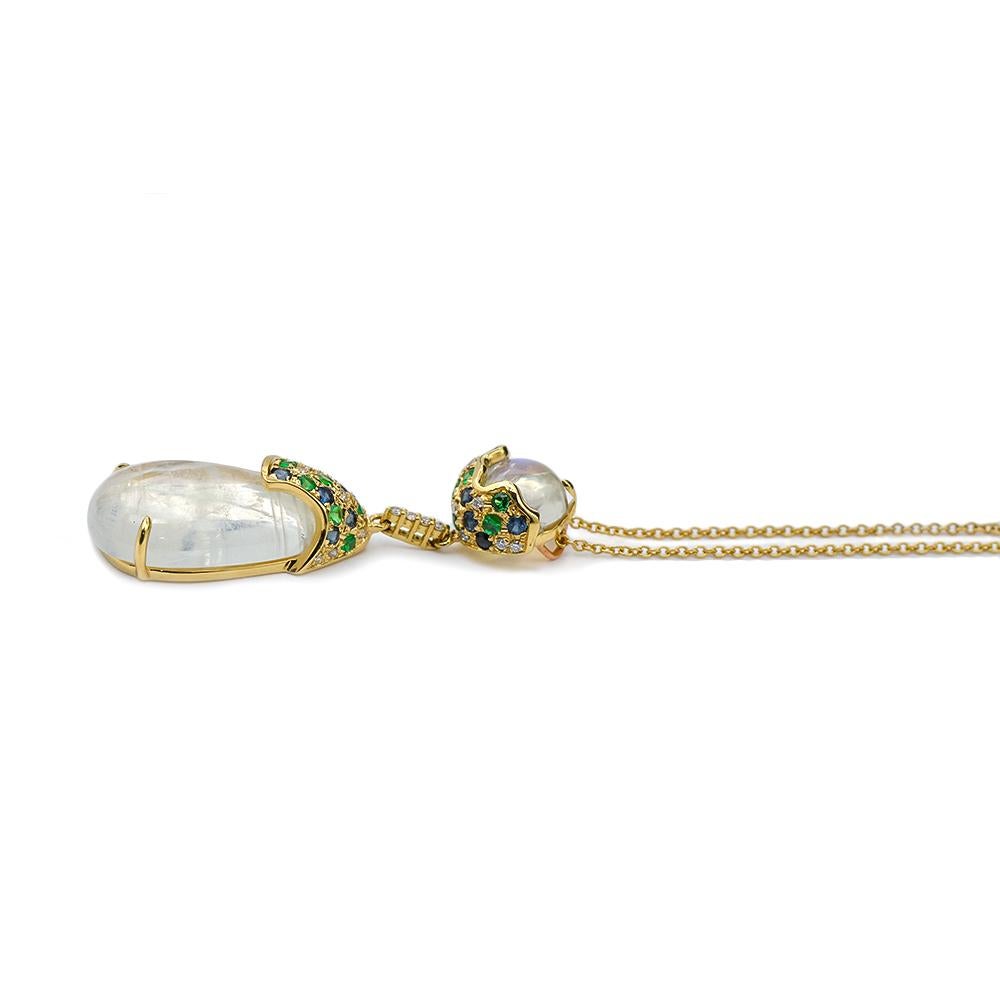 This necklace is crafted in 18kt yellow gold and features a 9.76 ct. pear shaped moonstone along with a 1.85 ct. round moonstone. The billowy adularescence is prominent in both moonstones and is further enhanced by an assortment of sapphires,