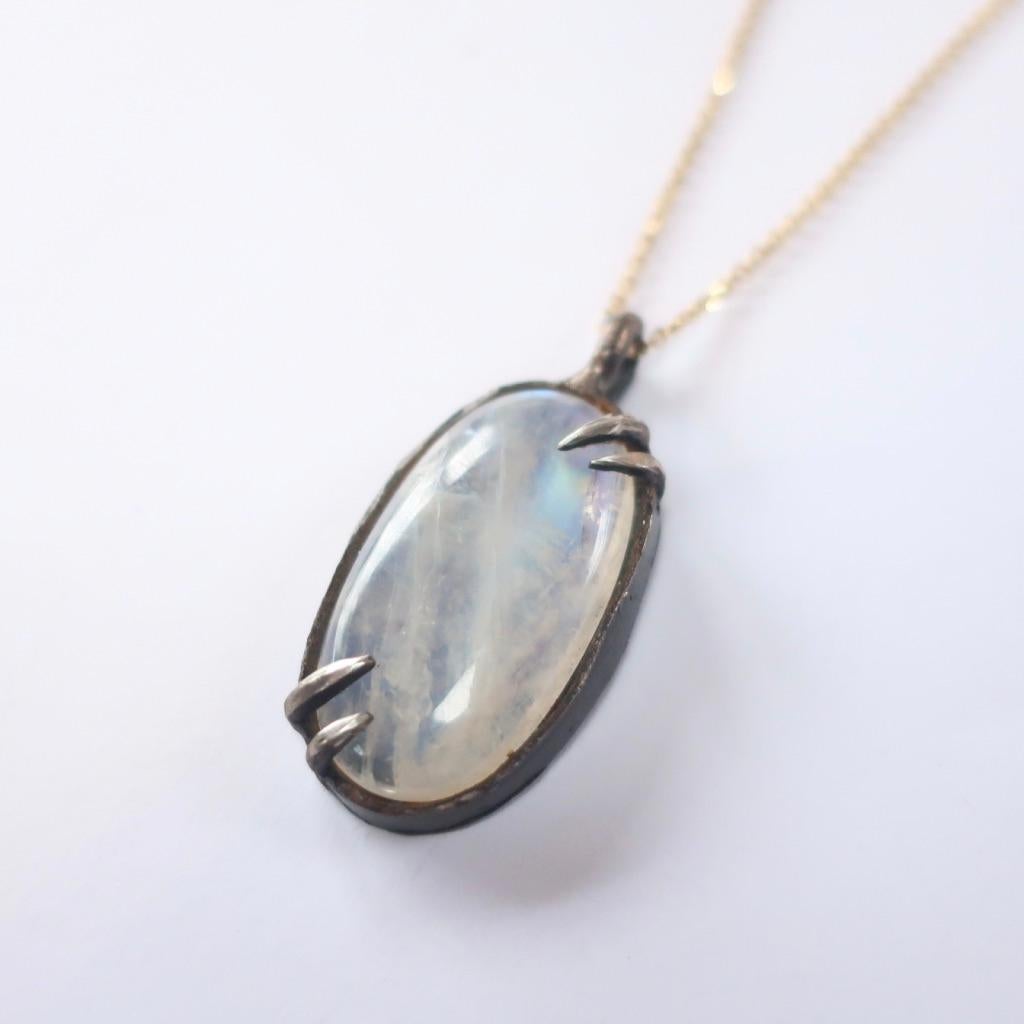 This Rainbow Moonstone stone is set in solid oxidized sterling silver and strung on a wonderful 20 inch solid gold chain. The stone measures 33x18mm and has a wonderful blue sheen.  Hand fabricated and handset. 