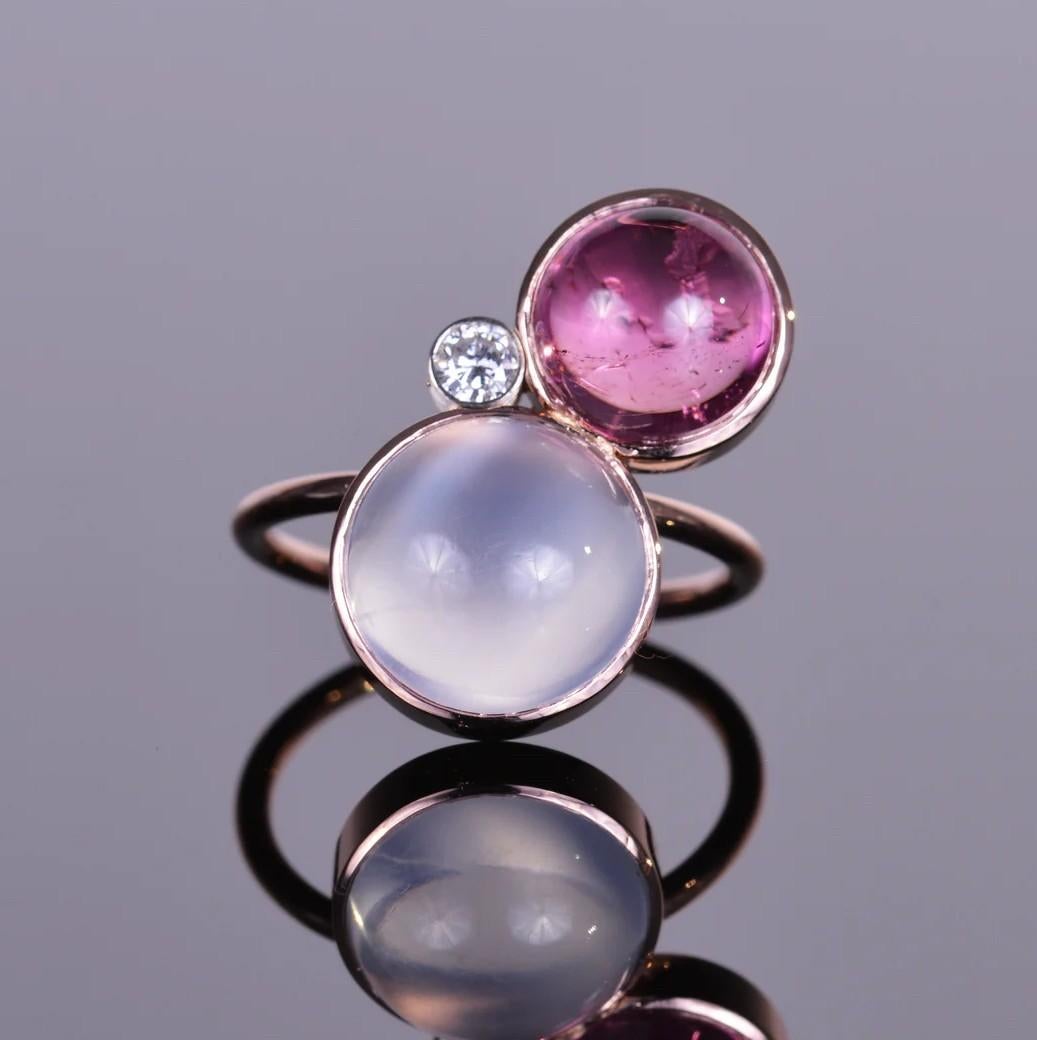 This geometric ring is made up of three different round stones, 5.87 carat moonstone, accented by 3.89 carat rubellite and a .10 carat brilliant cut natural diamond. All set in beautiful 14k rose gold. This is quite the trifecta, and makes for one