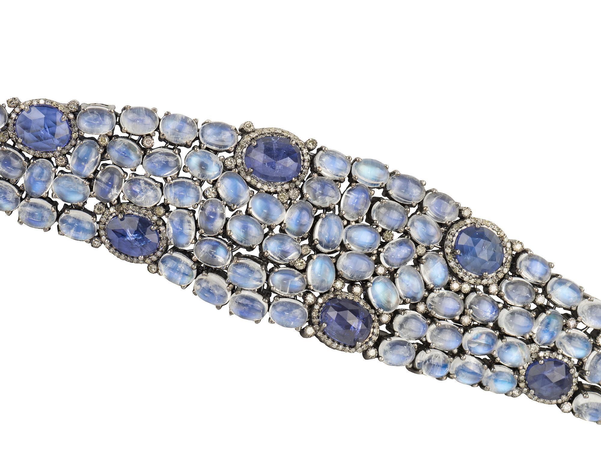 Blackened silver and gold strap bracelet, set with cabochon moonstones, and tanzanites, and 
could diamonds. Diamond weight approx 1.25 carats. Length 7.25.